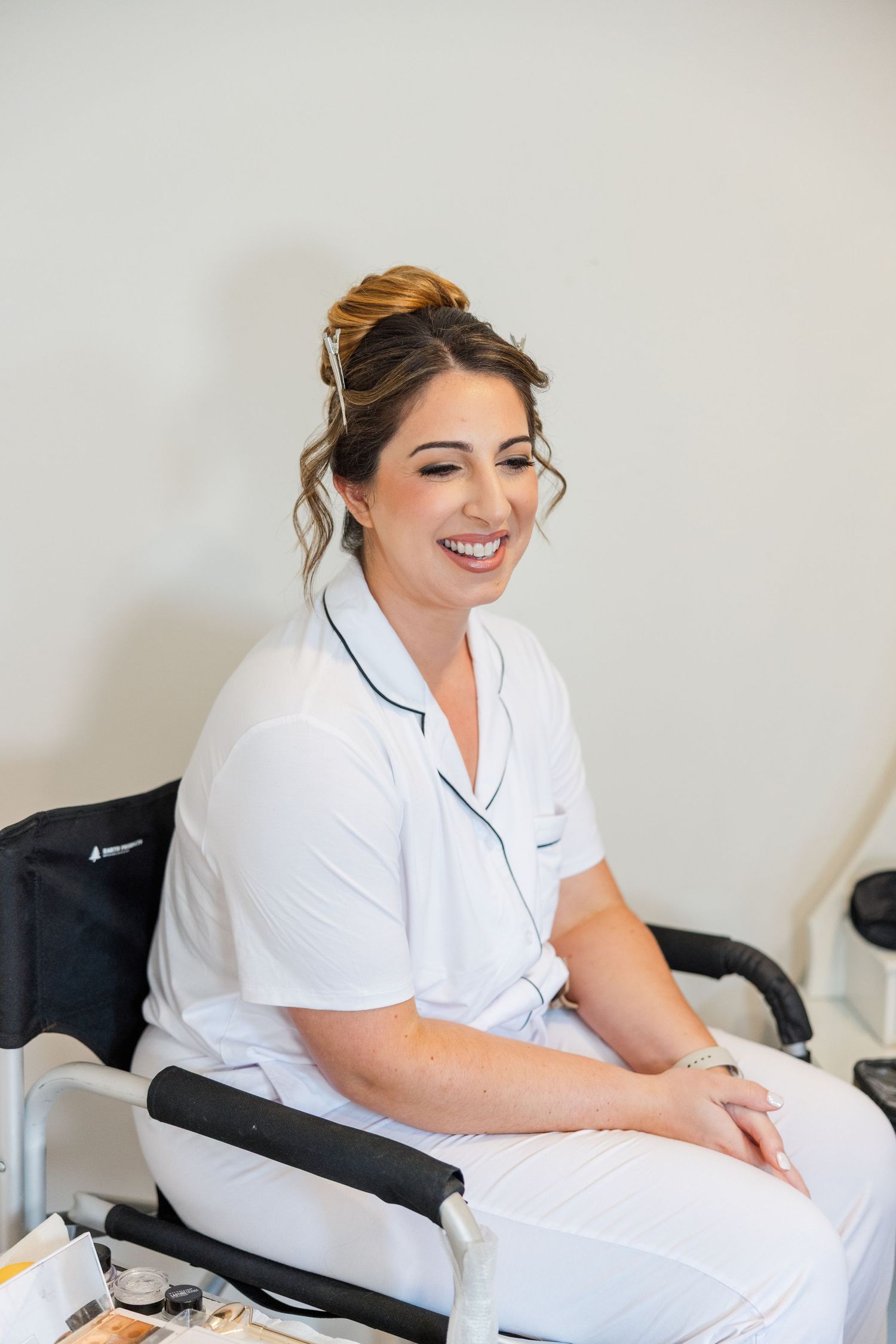 Healthcare professional in white uniform smiles while working at a desk in a medical office setting.