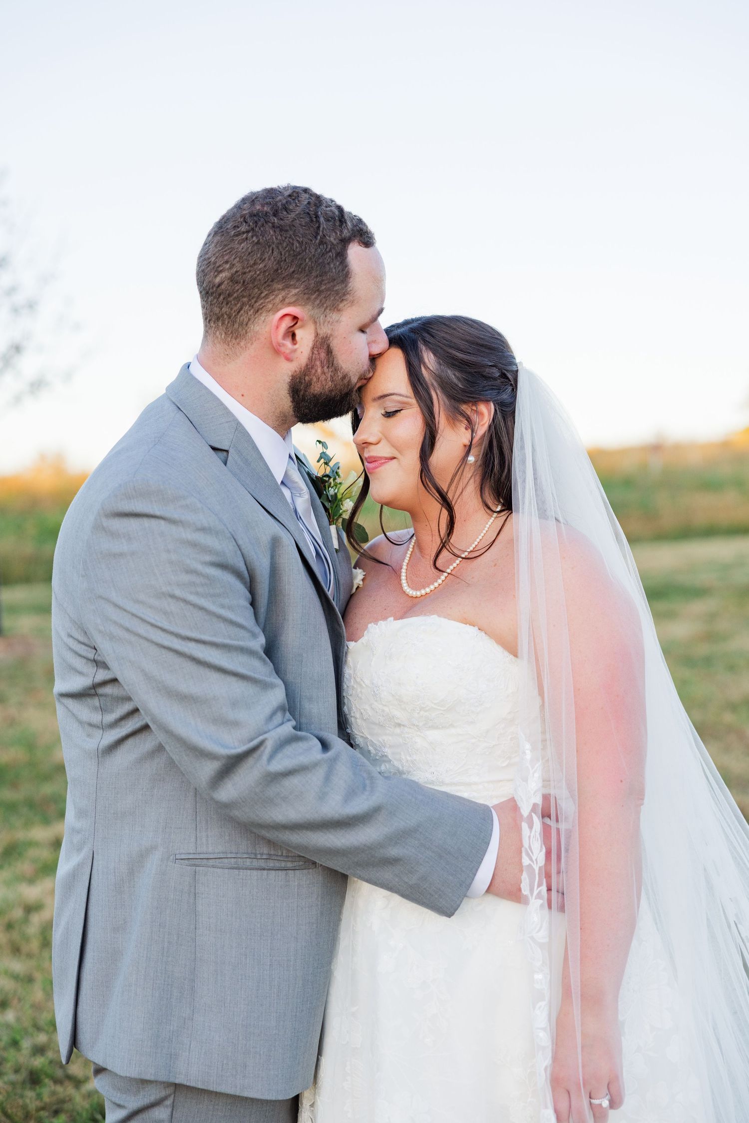 Intimate wedding couple portraits in a field during golden hour.
