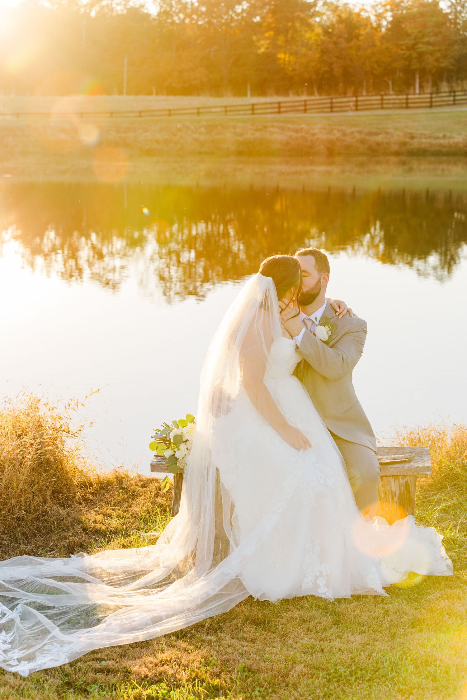 Wedding couple poses for romantic sunset photos by a serene lake with golden light.