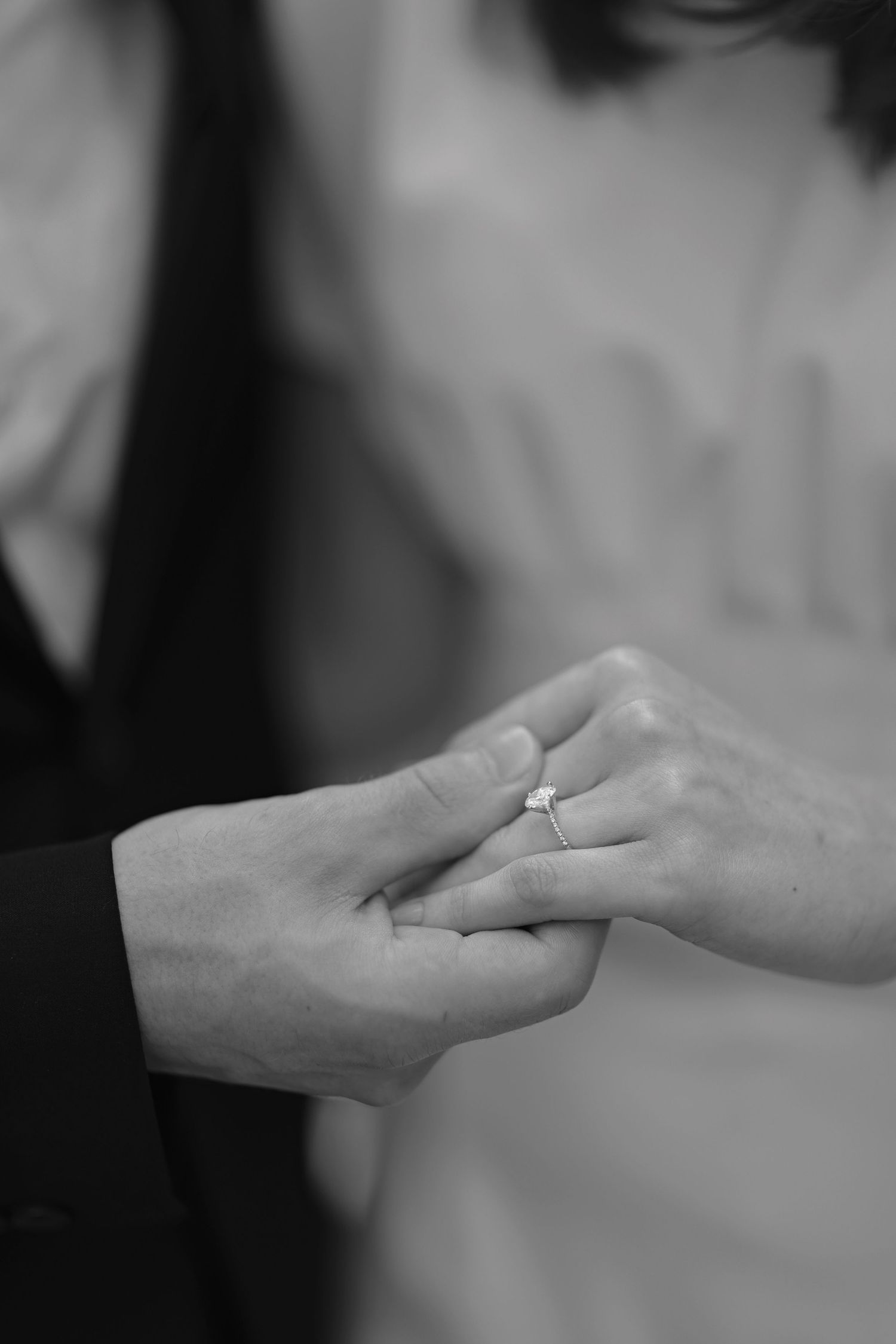 Close-up black and white shot of hands exchanging a wedding ring.