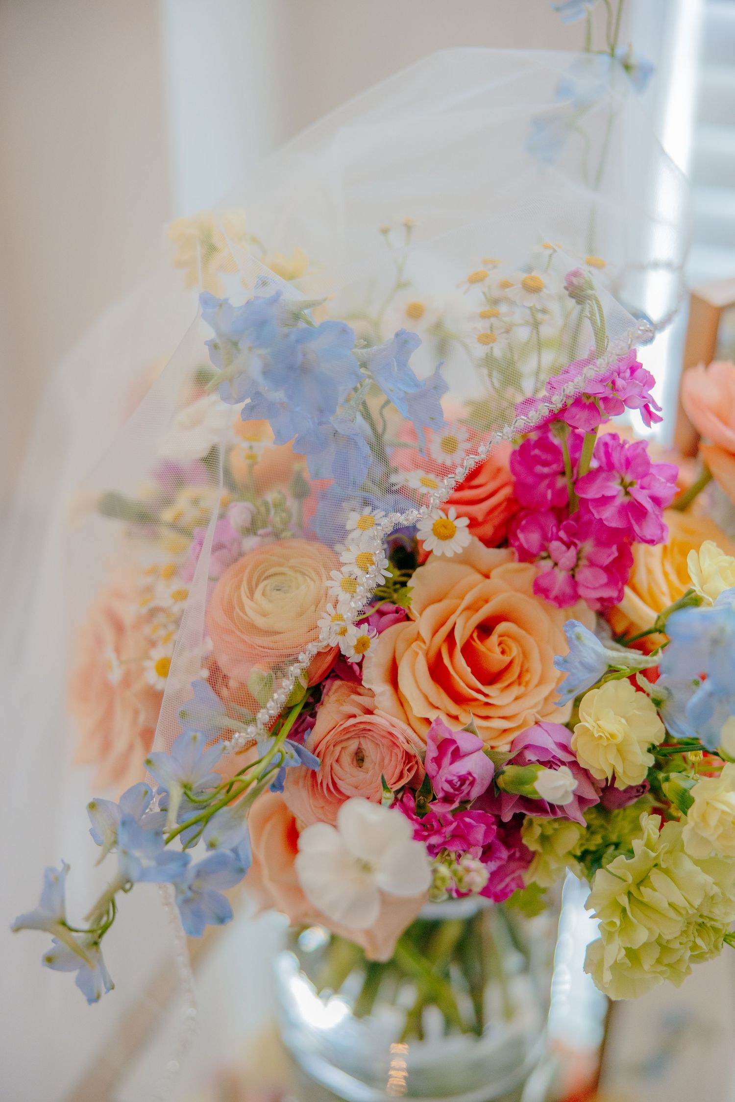 Romantic wedding bouquet with peach roses and mixed pastel flowers against white backdrop.