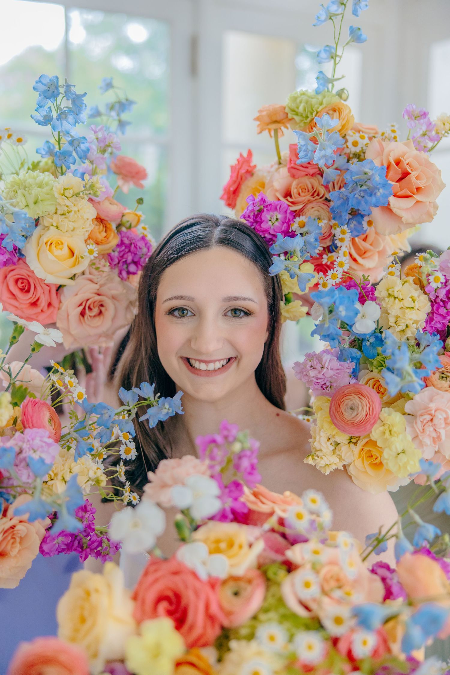 Vibrant spring flowers in blue, pink, and yellow create a colorful wedding bouquet display.