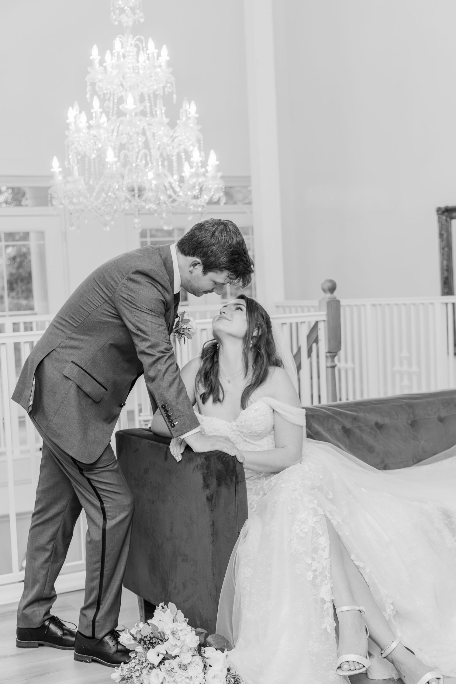 Romantic wedding moment under elegant crystal chandelier in black and white photography.