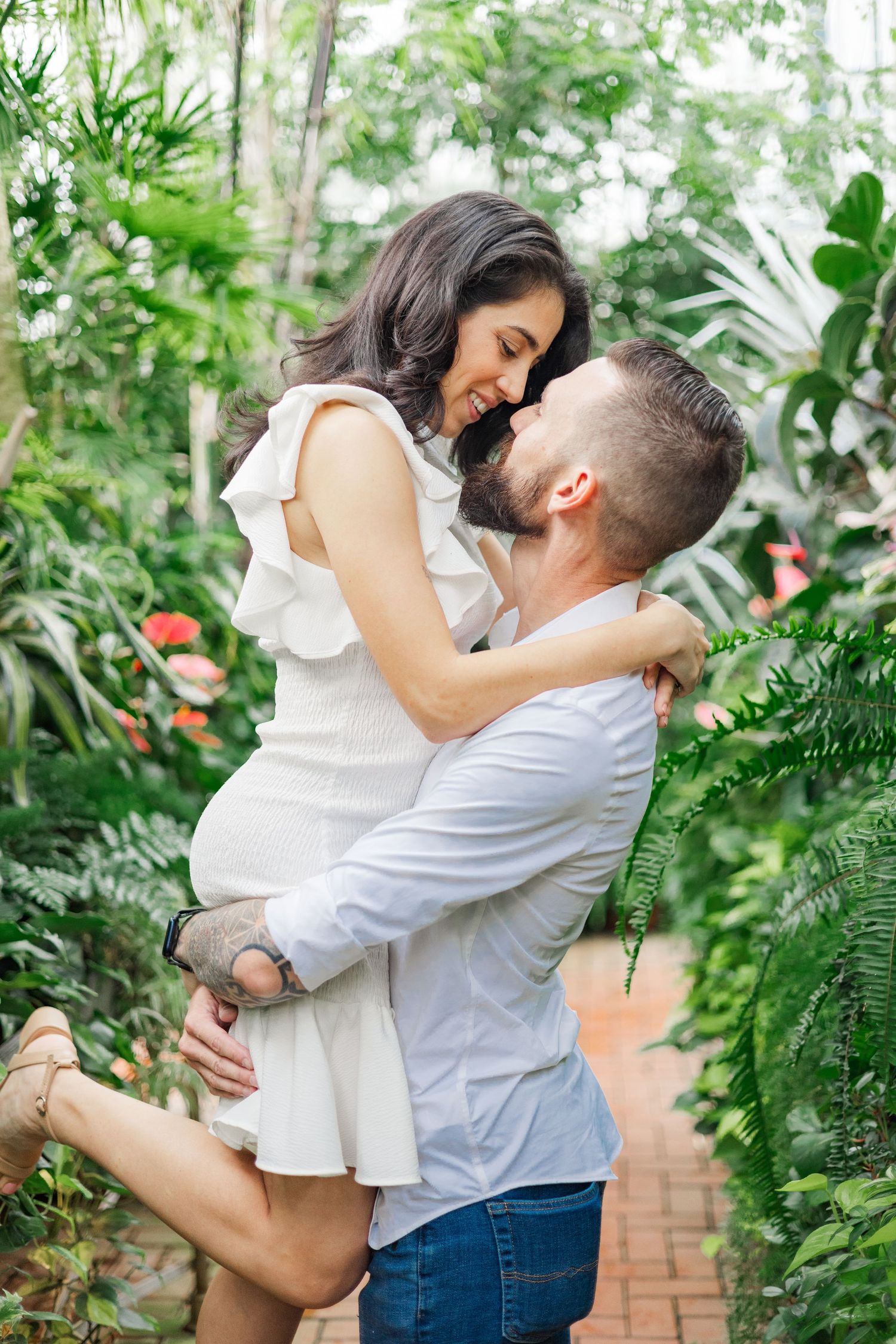 A joyful dance sequence captured among tropical plants and brick walls in a greenhouse.