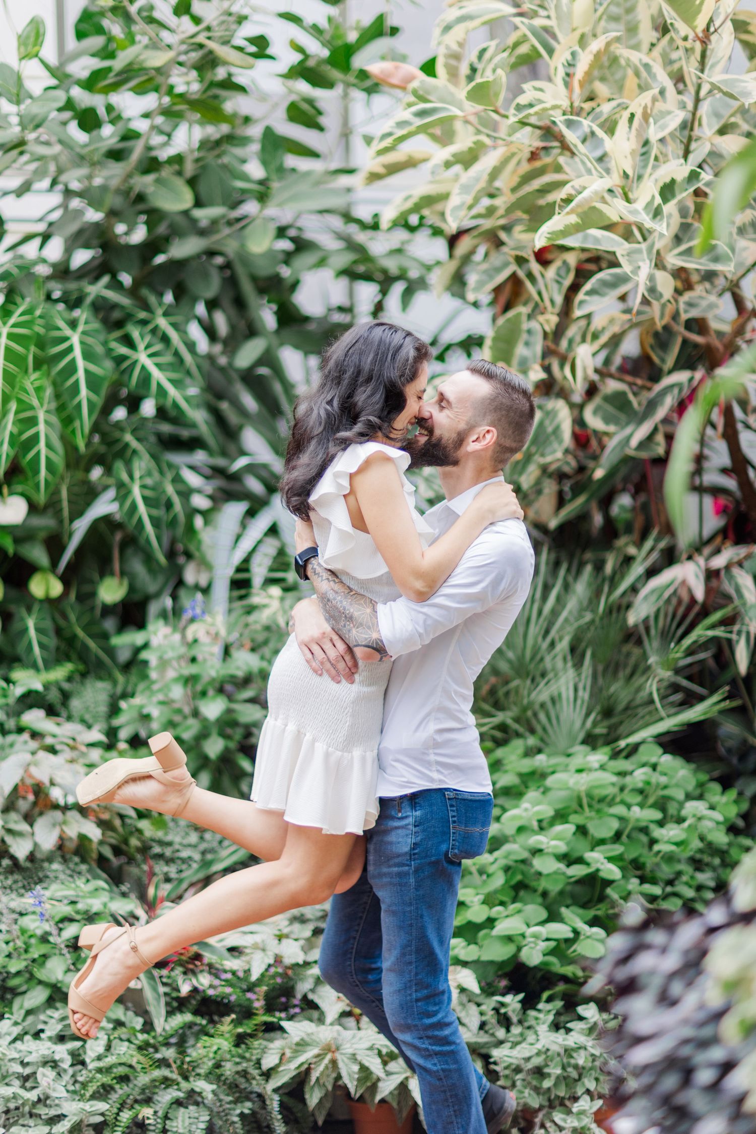 Romantic embrace in a lush garden setting with tropical plants.