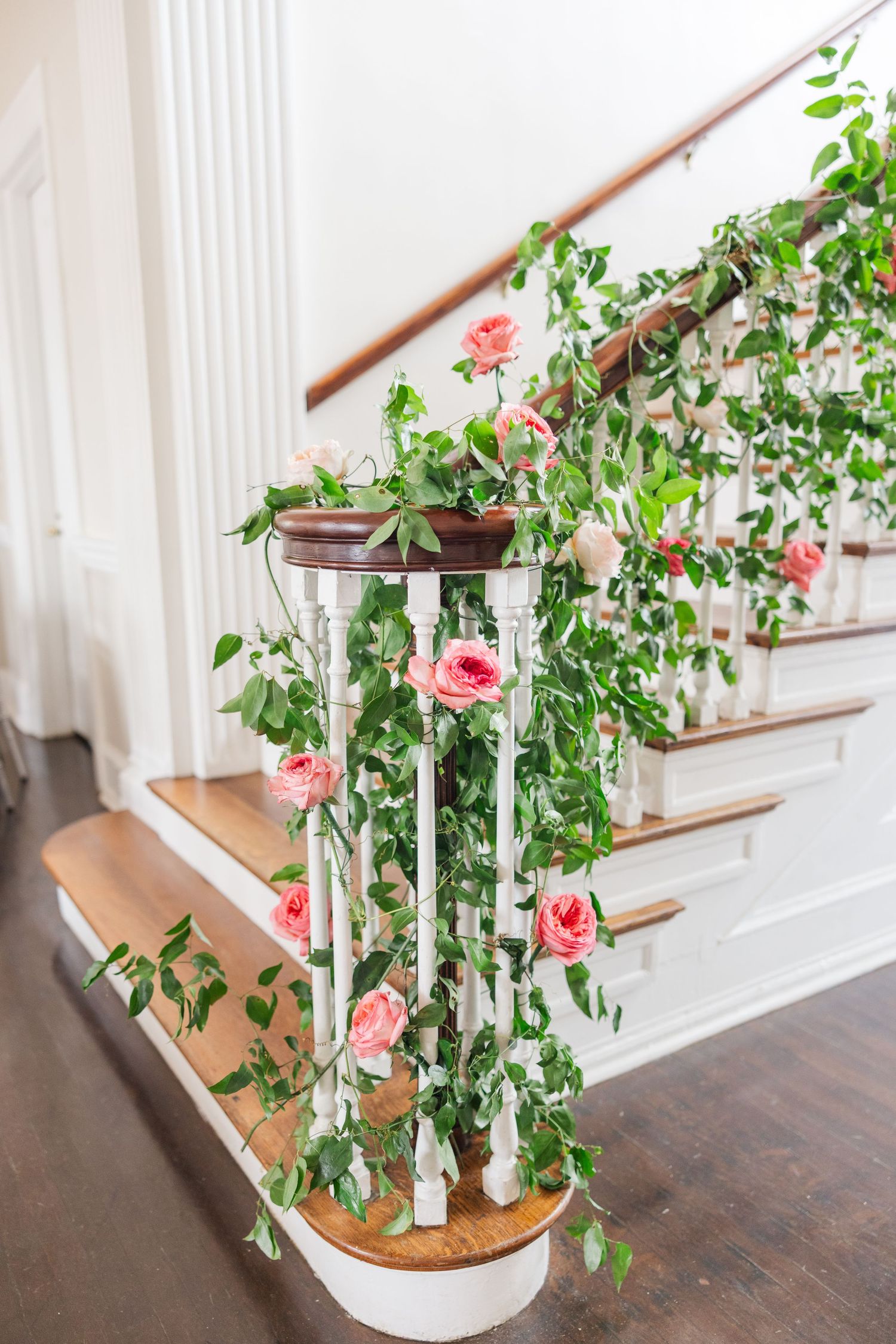 Elegant staircase decorated with pink roses and white candle holders.
