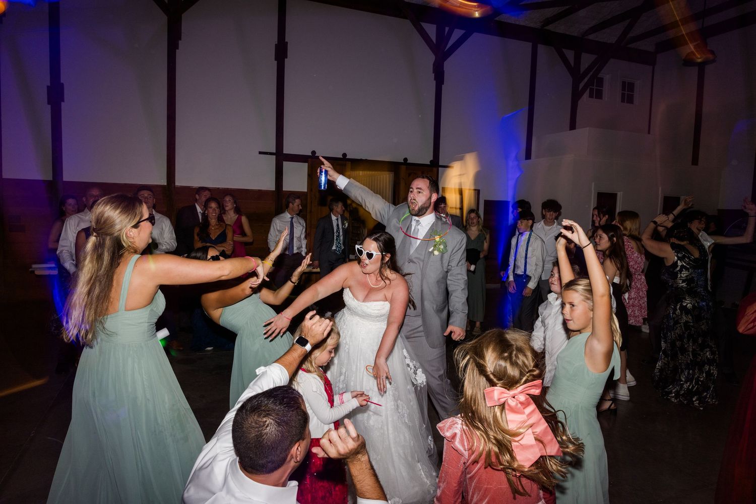 Wedding party dancing and celebrating at a reception with blue mood lighting.