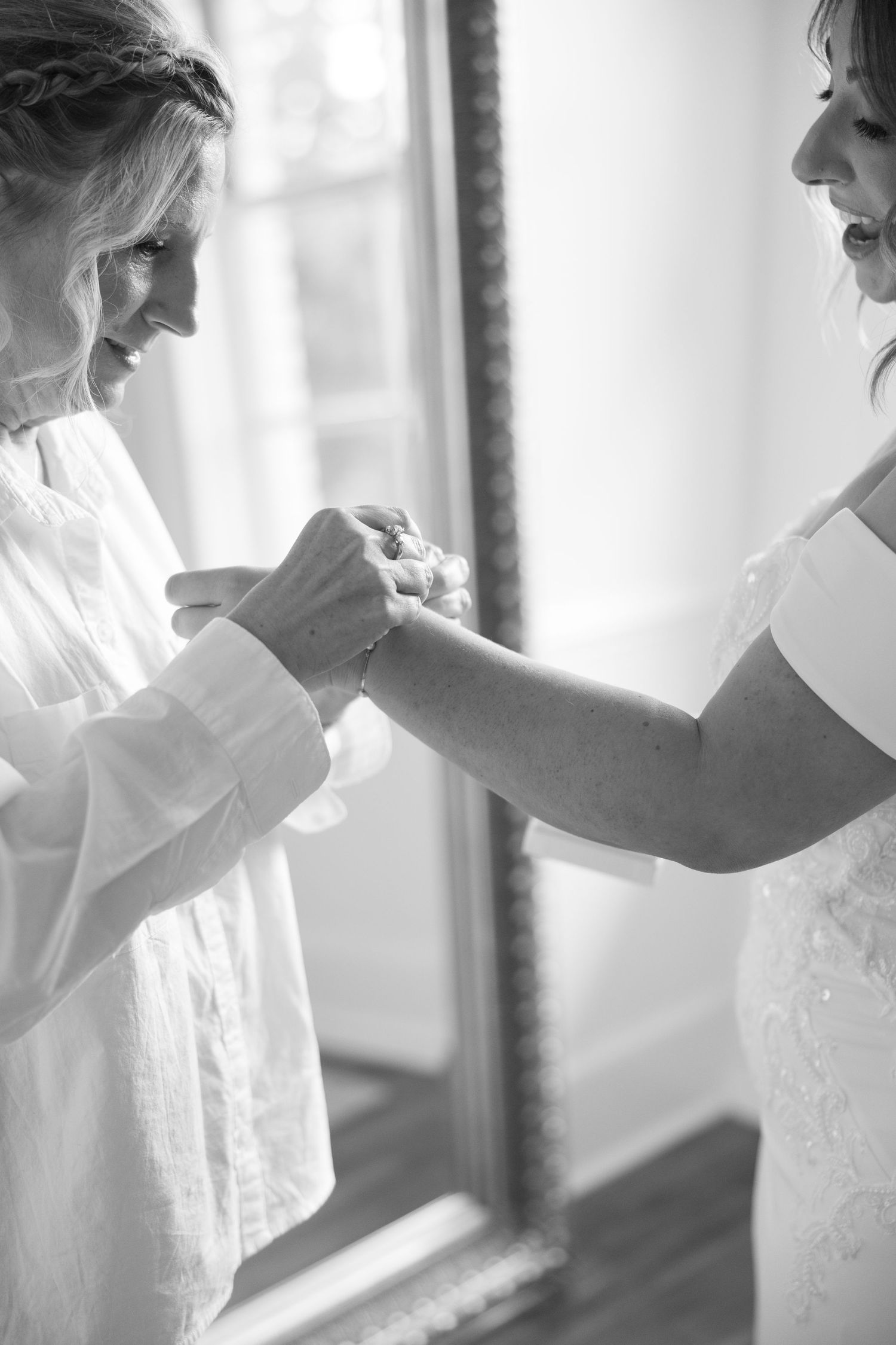 Close-up black and white shots of wedding dress details being adjusted.