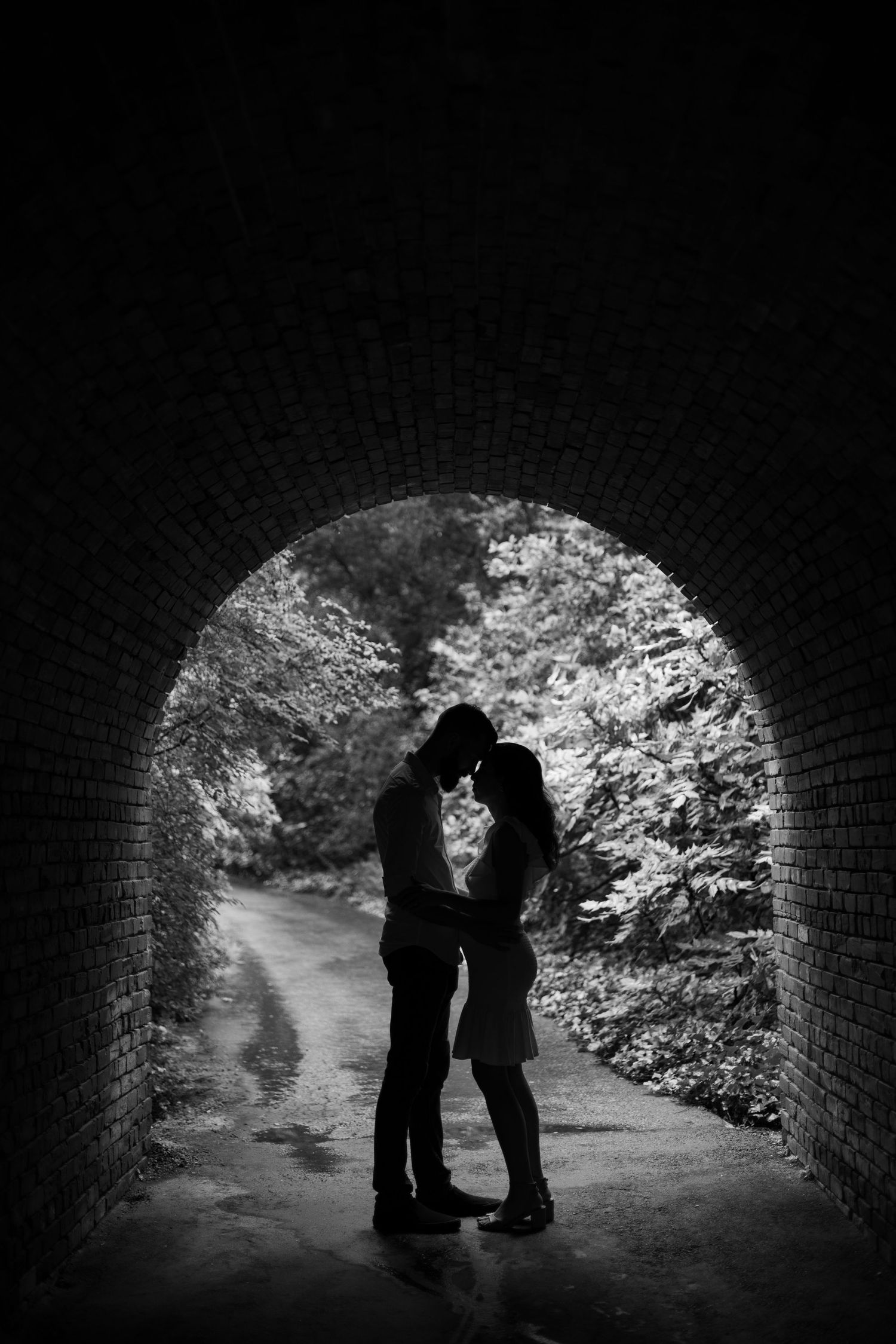 Silhouetted figures in a brick tunnel with natural light streaming through.
