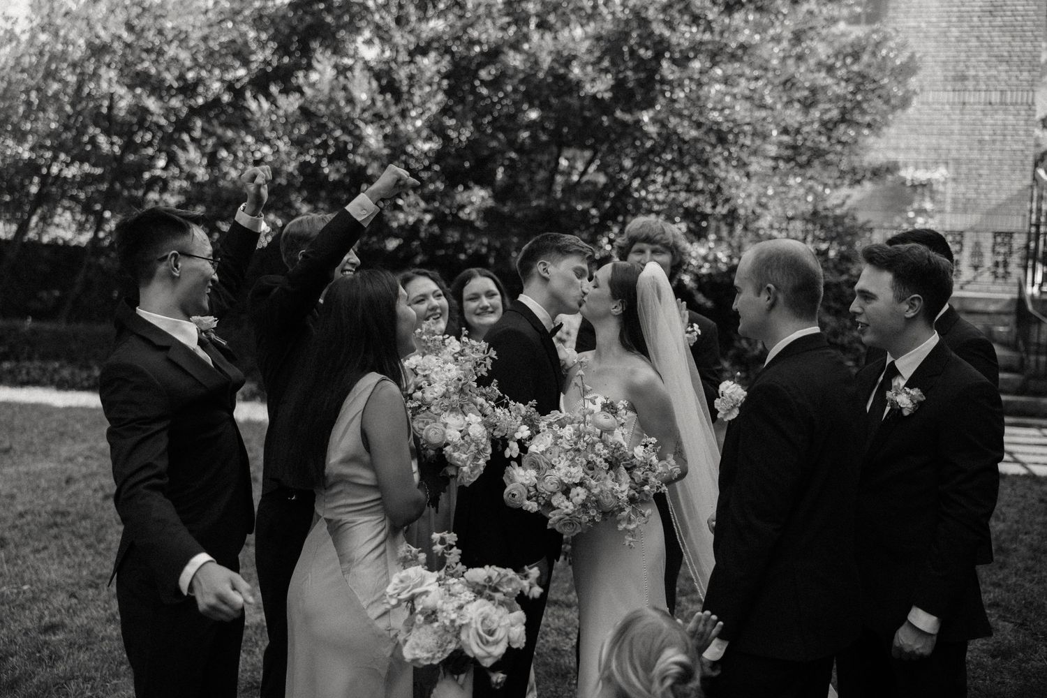 Wedding party gathers for formal outdoor ceremony photos.