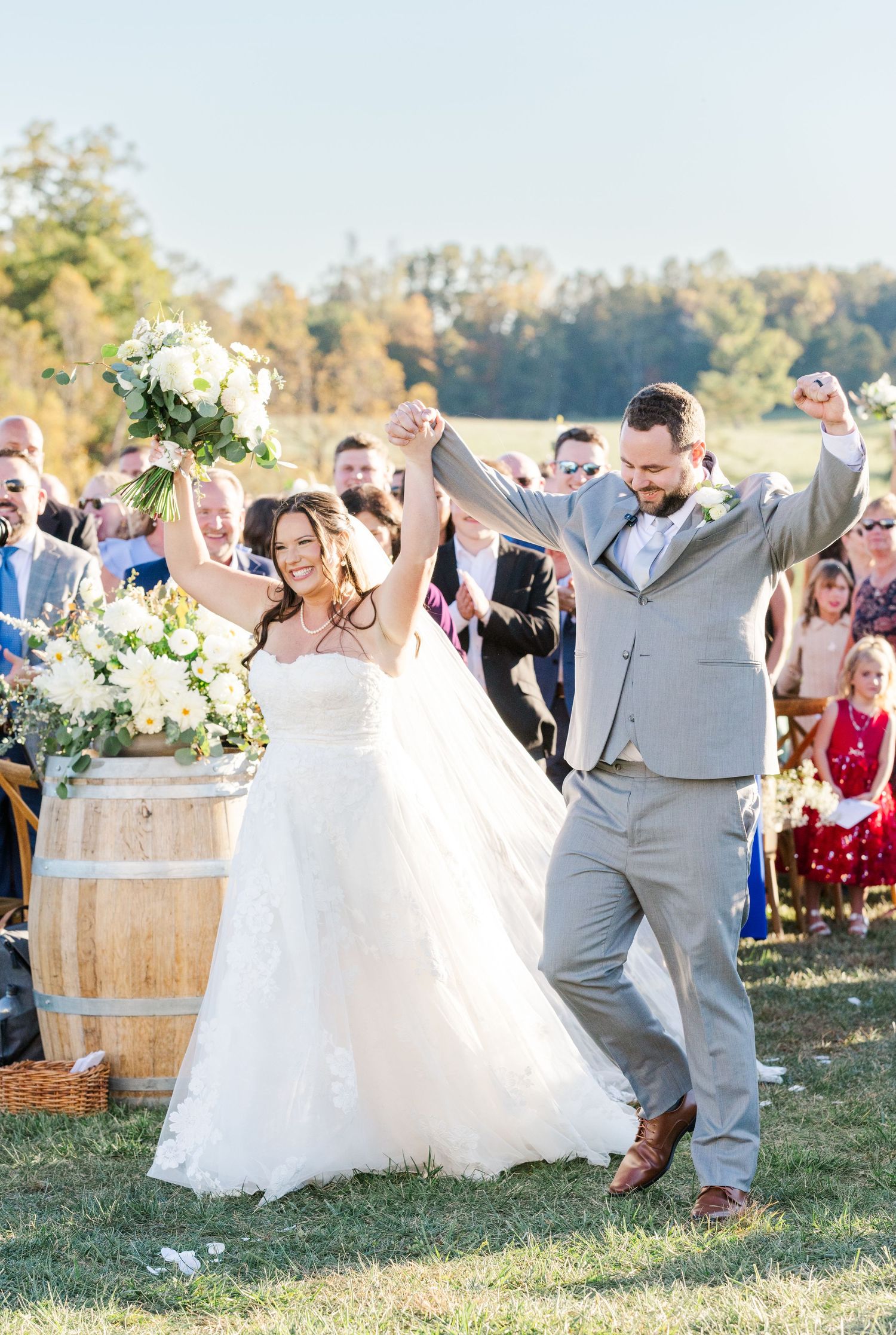 Wedding celebration on sunny outdoor lawn with guests dancing and celebrating.