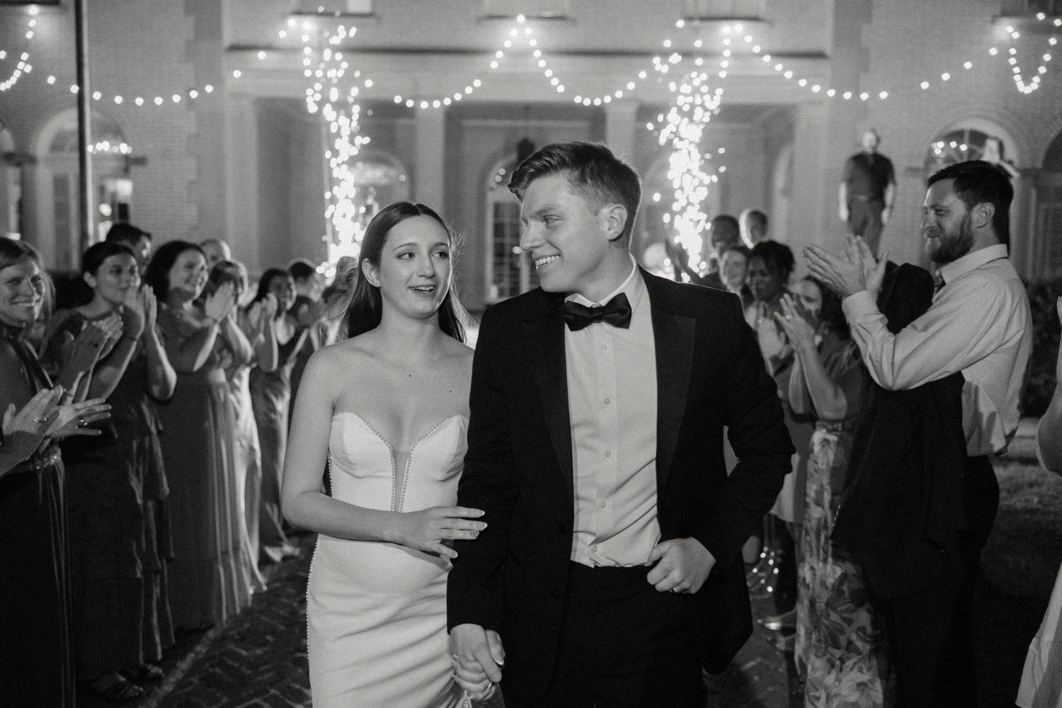 Wedding reception dance floor with string lights and couples dancing in formal attire.