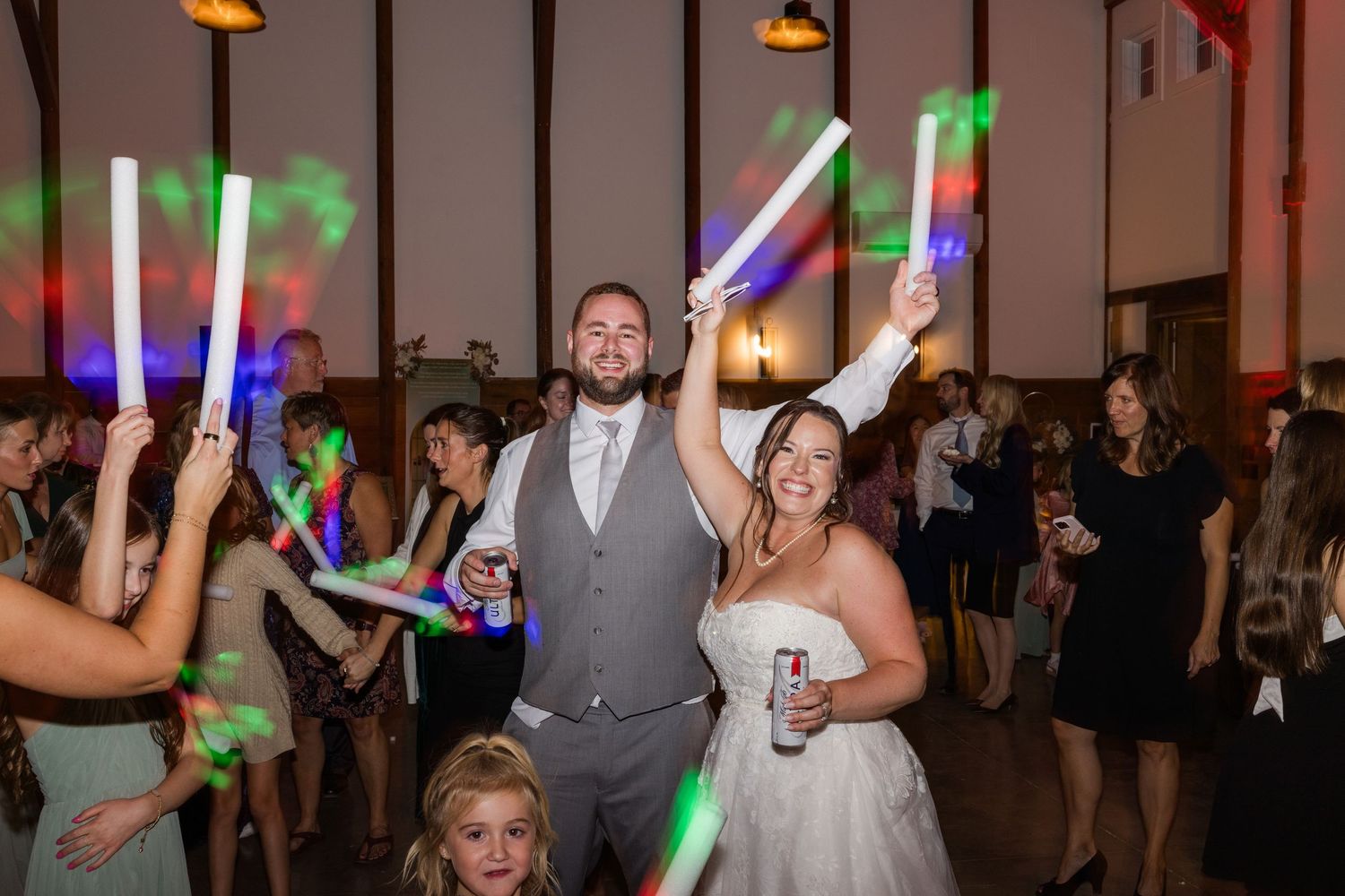 Wedding reception dance floor filled with guests holding colorful light-up sticks during celebrations.