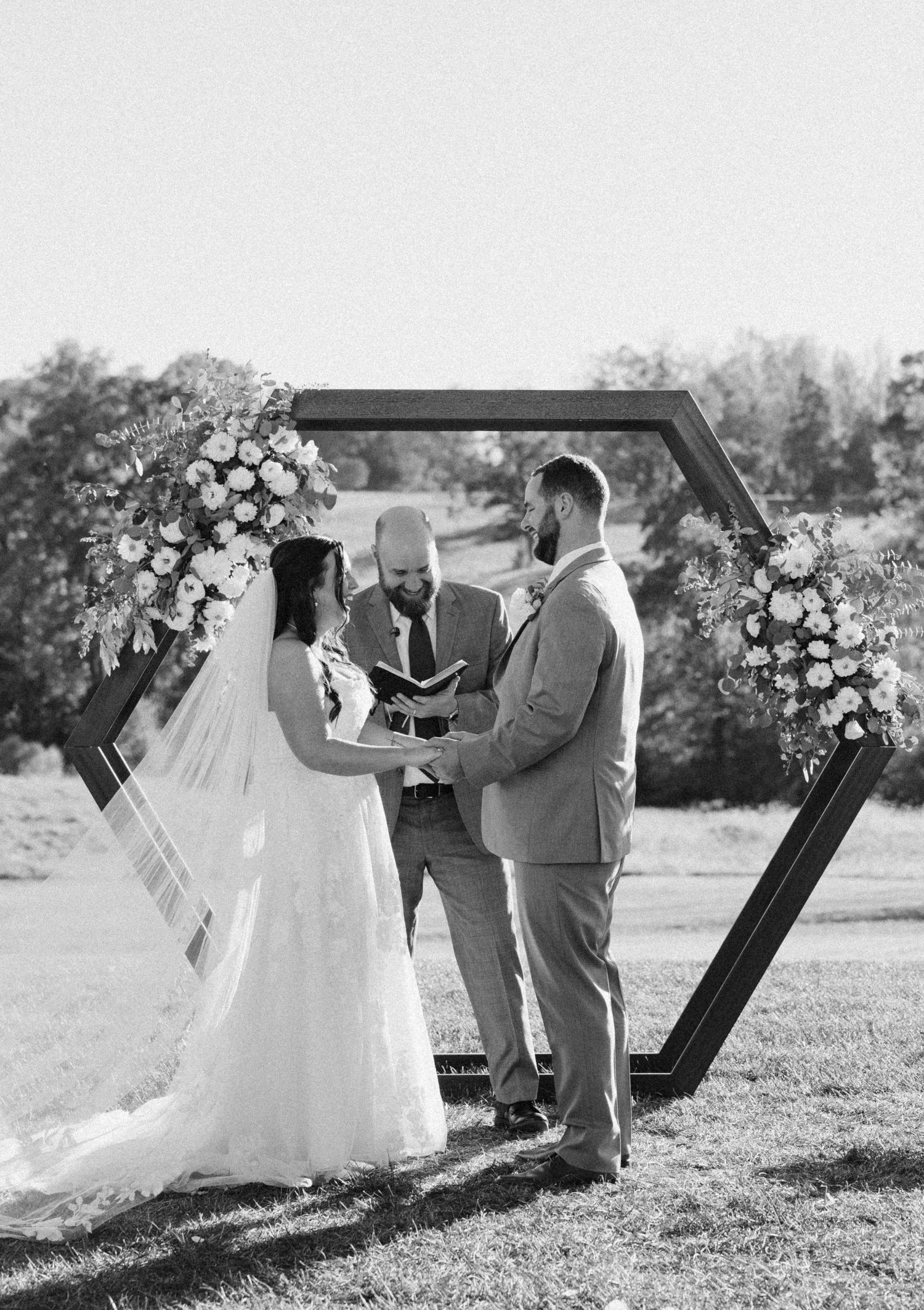Black and white wedding photos showing couple posing with geometric arch in outdoor setting.