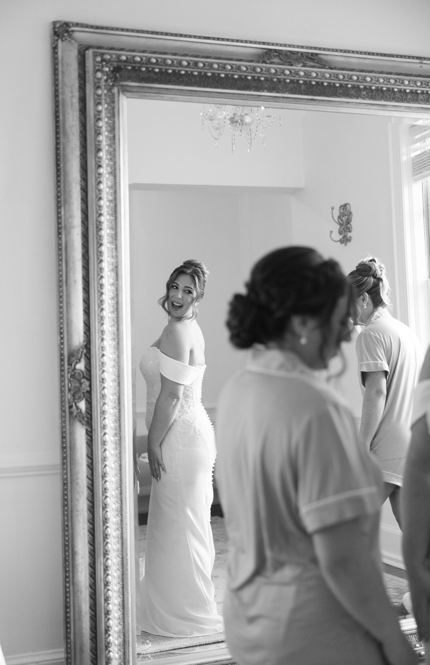 Black and white sequence showing someone hanging a decorative mirror on a white wall.