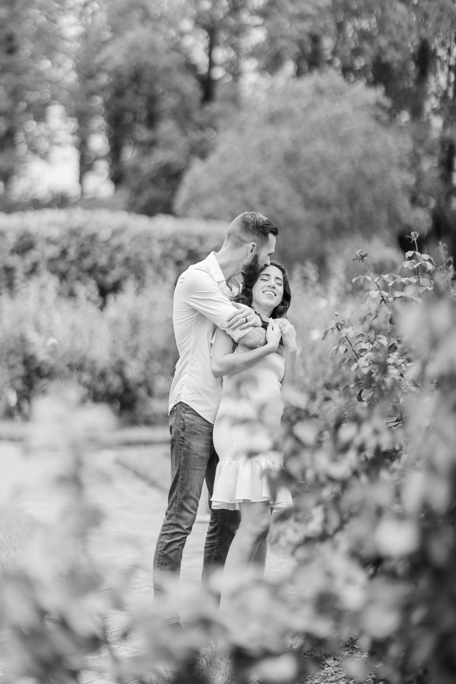 A romantic black and white photo sequence captured through garden foliage.
