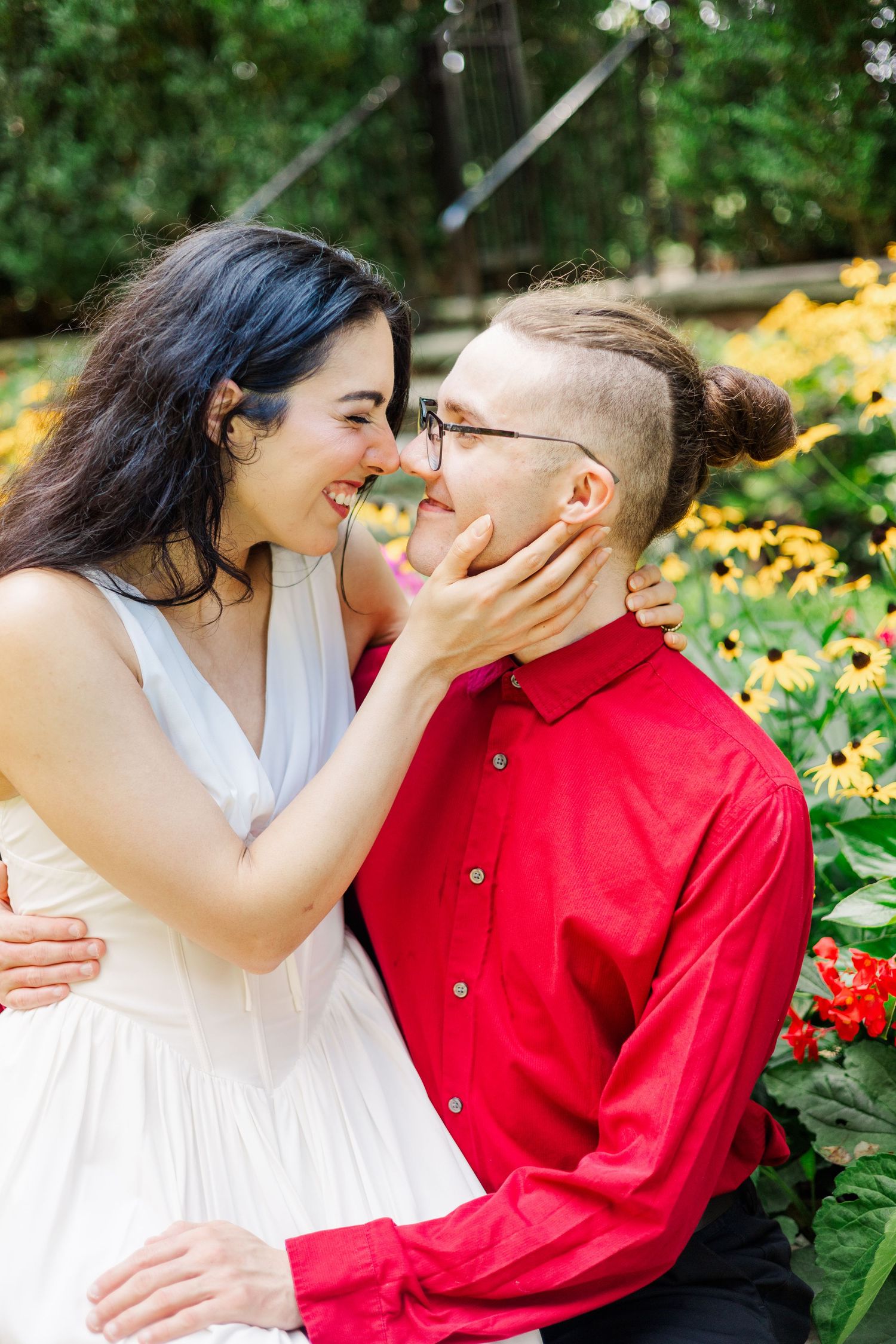 A romantic couple shares a tender moment in a garden with blooming yellow flowers.