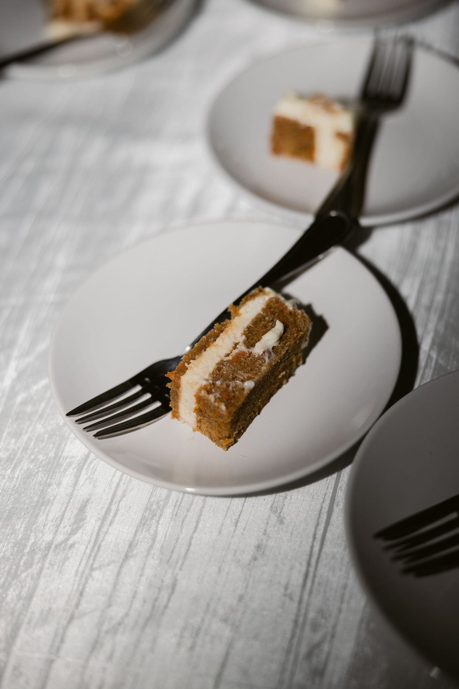 Close-up of a slice of wedding cake on a white plate with a silver fork.