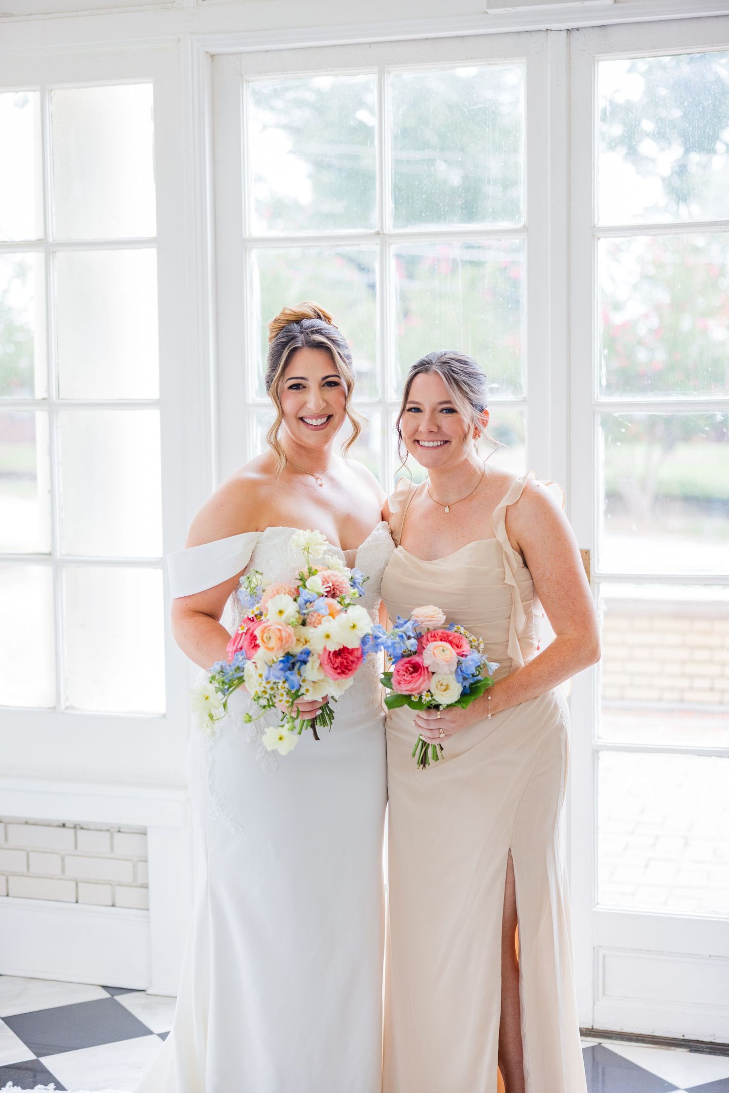 Bridal party holding colorful bouquets while posing in a light-filled room.
