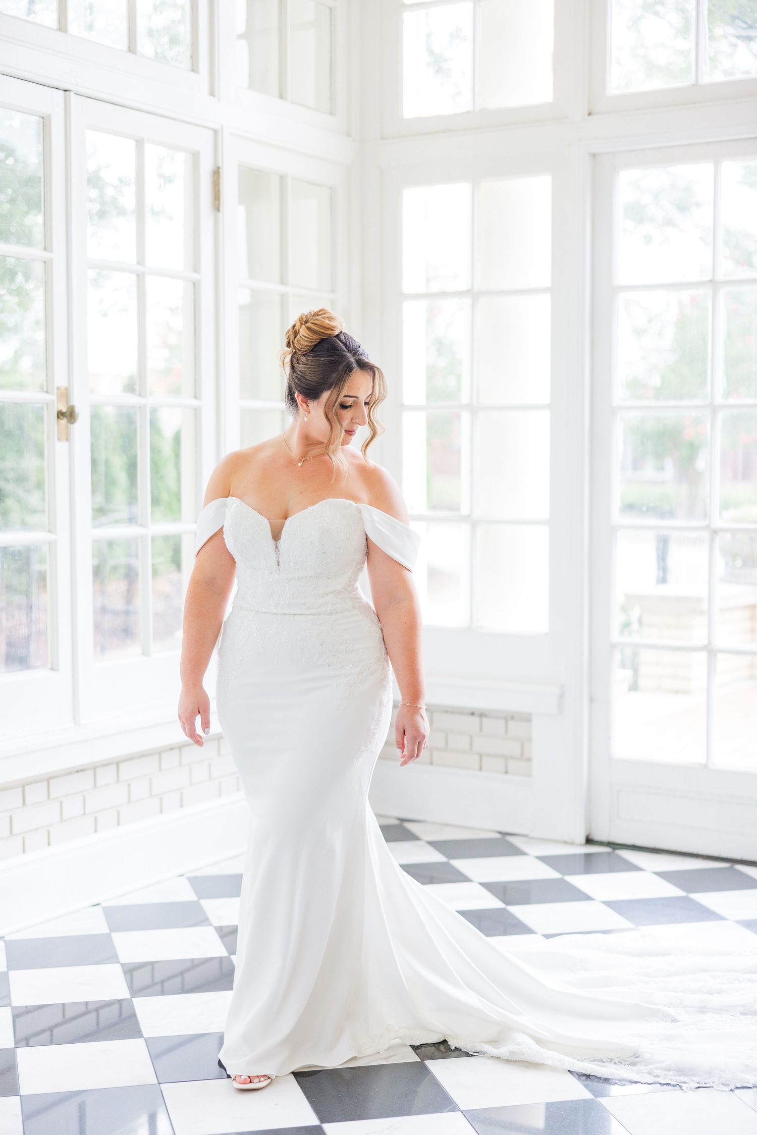 Bride twirling in a white wedding dress in a bright sunlit room with checkered floors.