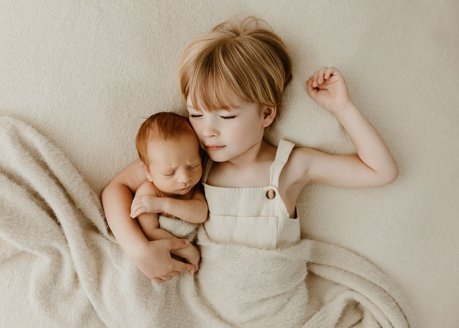 Intimate family moment with baby resting on soft beige blanket.