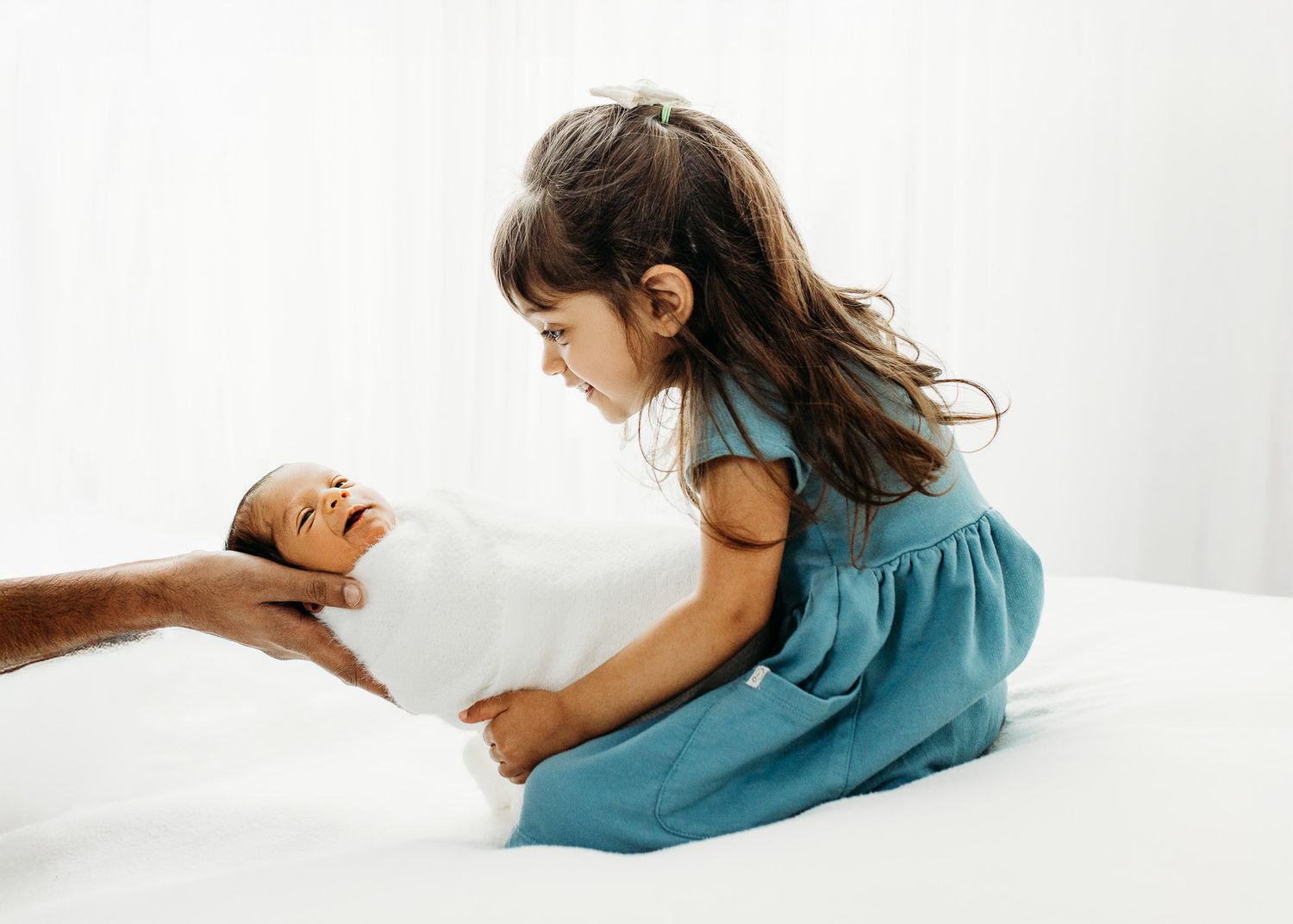 Newborn baby sleeping peacefully wrapped in soft teal blanket against white background.