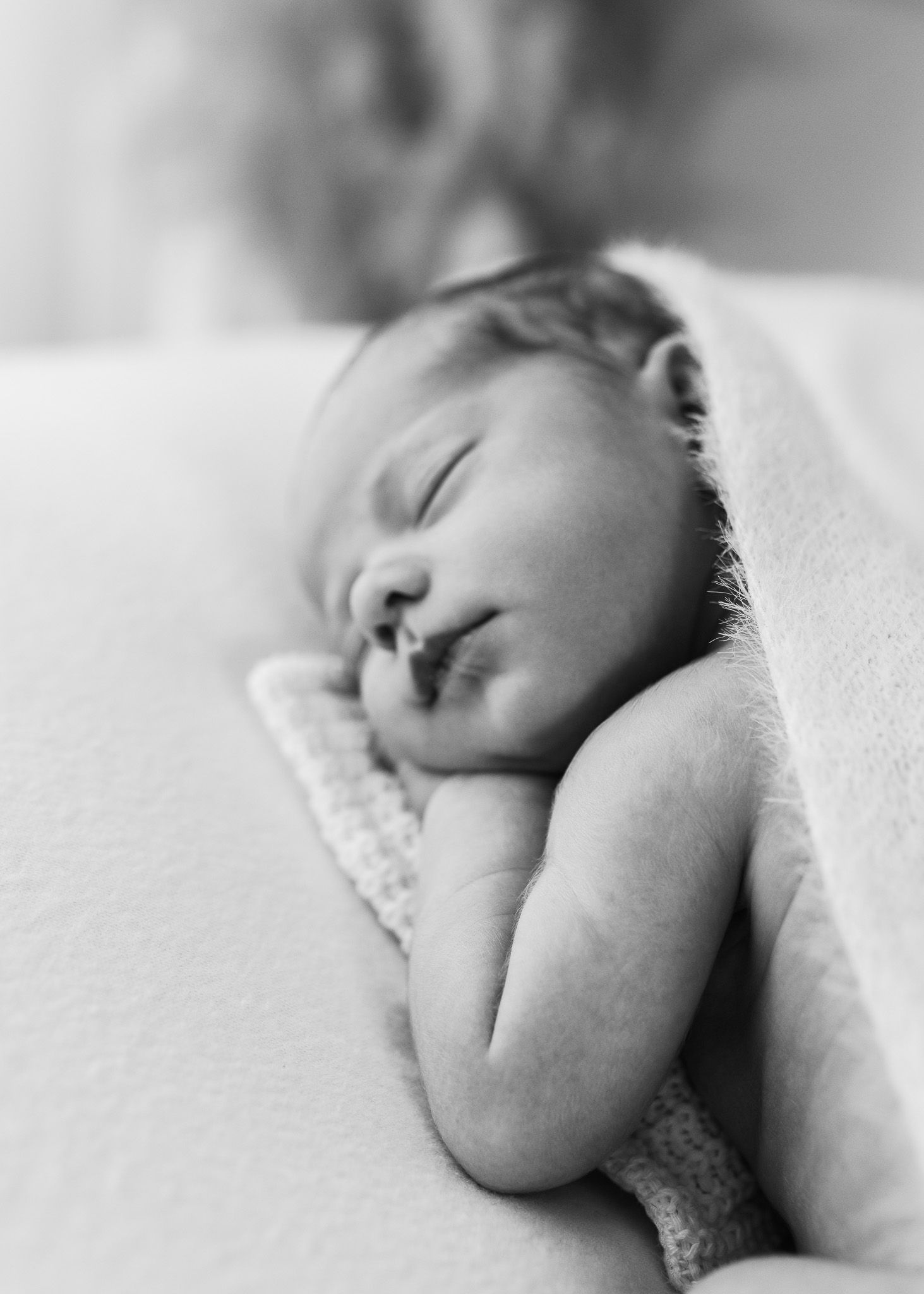 Peaceful sleeping infant on white bedding captured in black and white photography.
