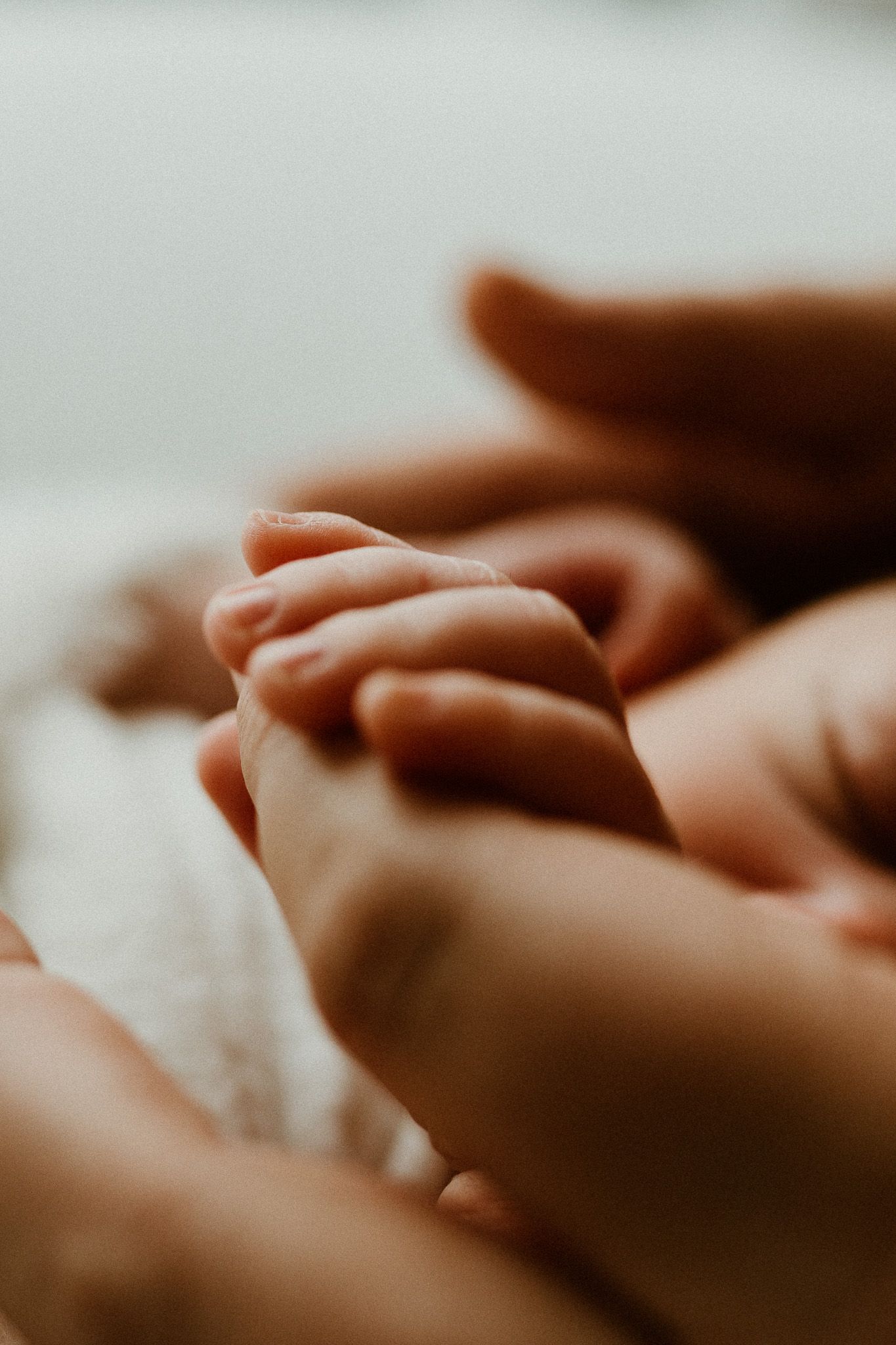 Soft focus image of hands tenderly touching against a light background.
