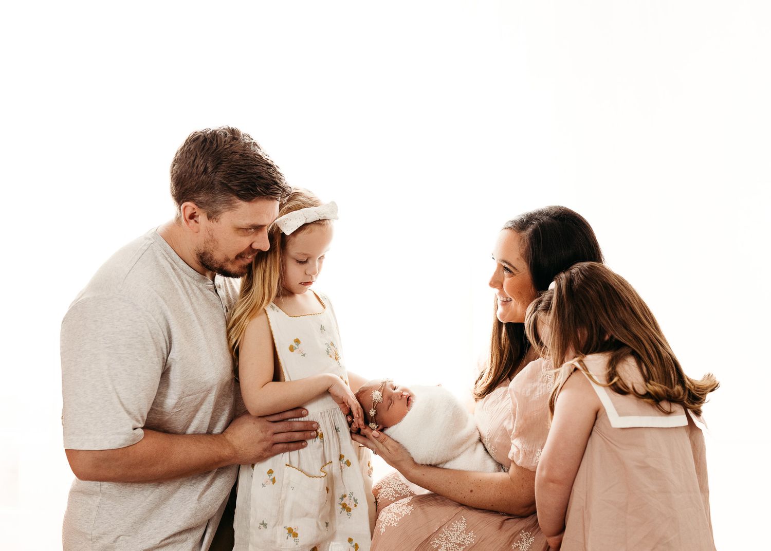 Family portrait series showing tender moments with newborn in neutral tones.