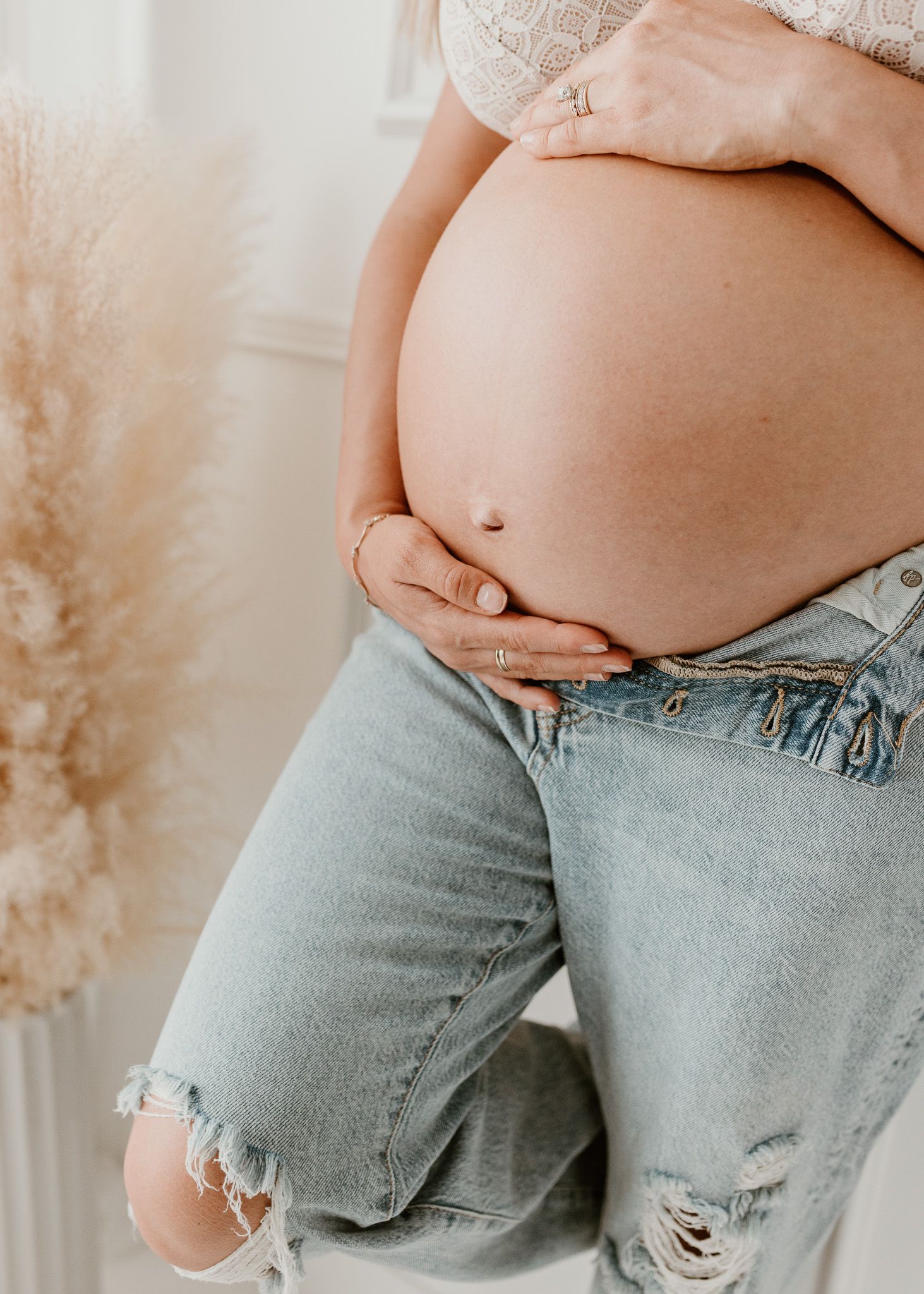Series of images showing pregnant belly in distressed denim jeans.