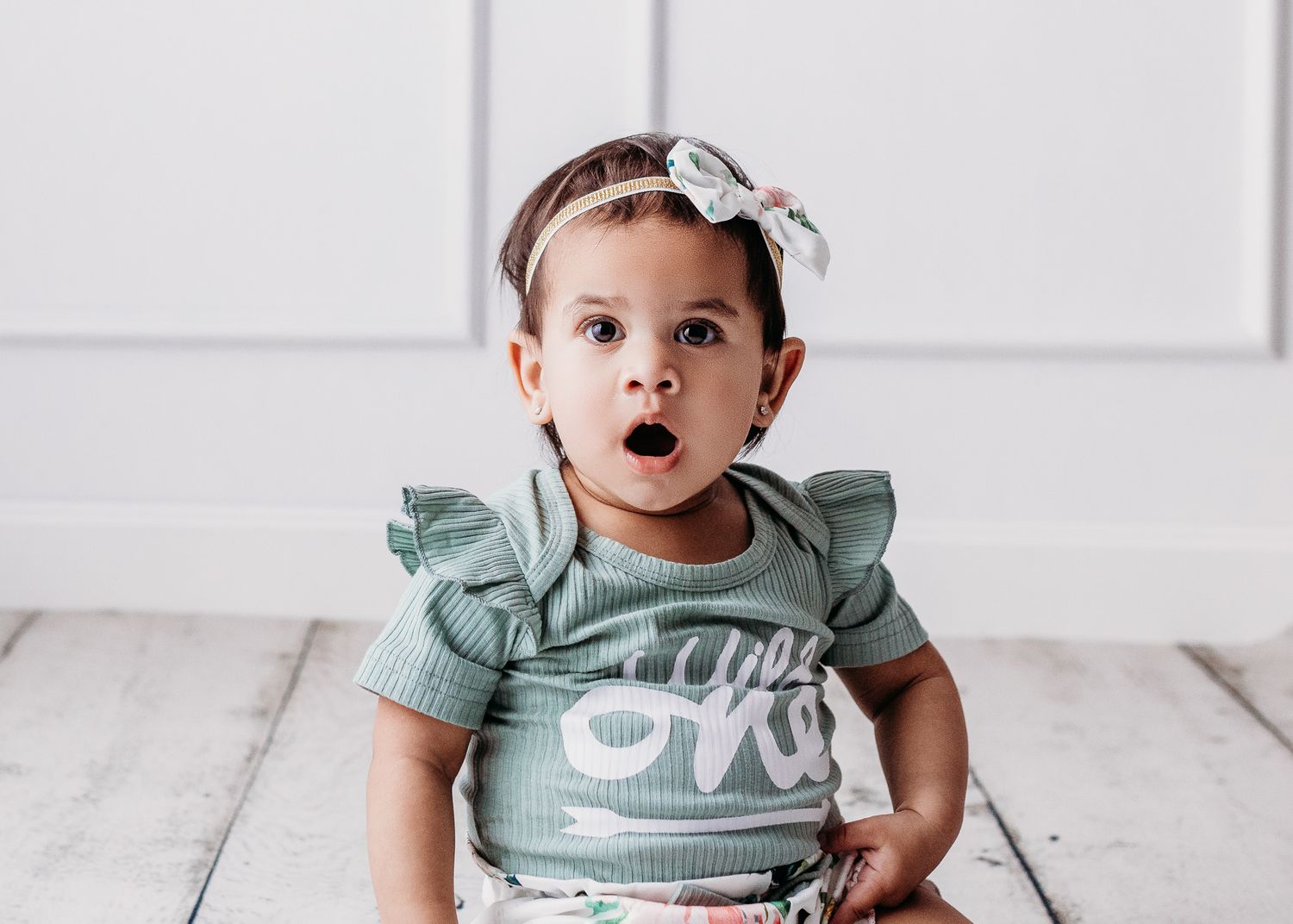 Baby wearing mint green ruffled outfit during milestone photo session.
