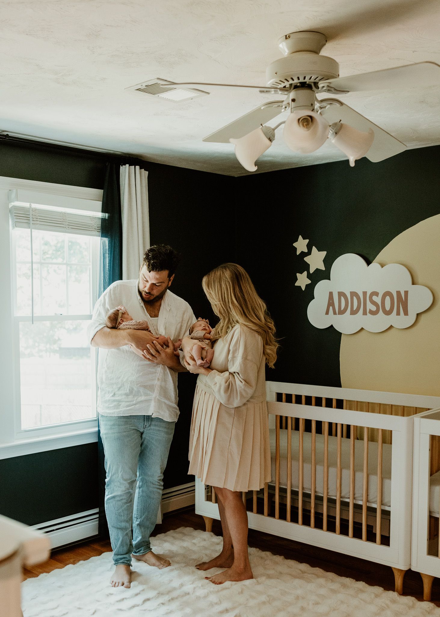 Nursery room with cloud decorations and white crib against dark accent wall.