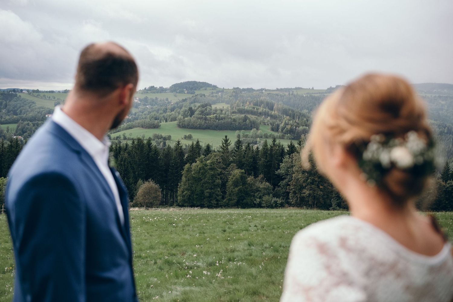 Couple overlooking a scenic mountain landscape with forests and rolling hills.