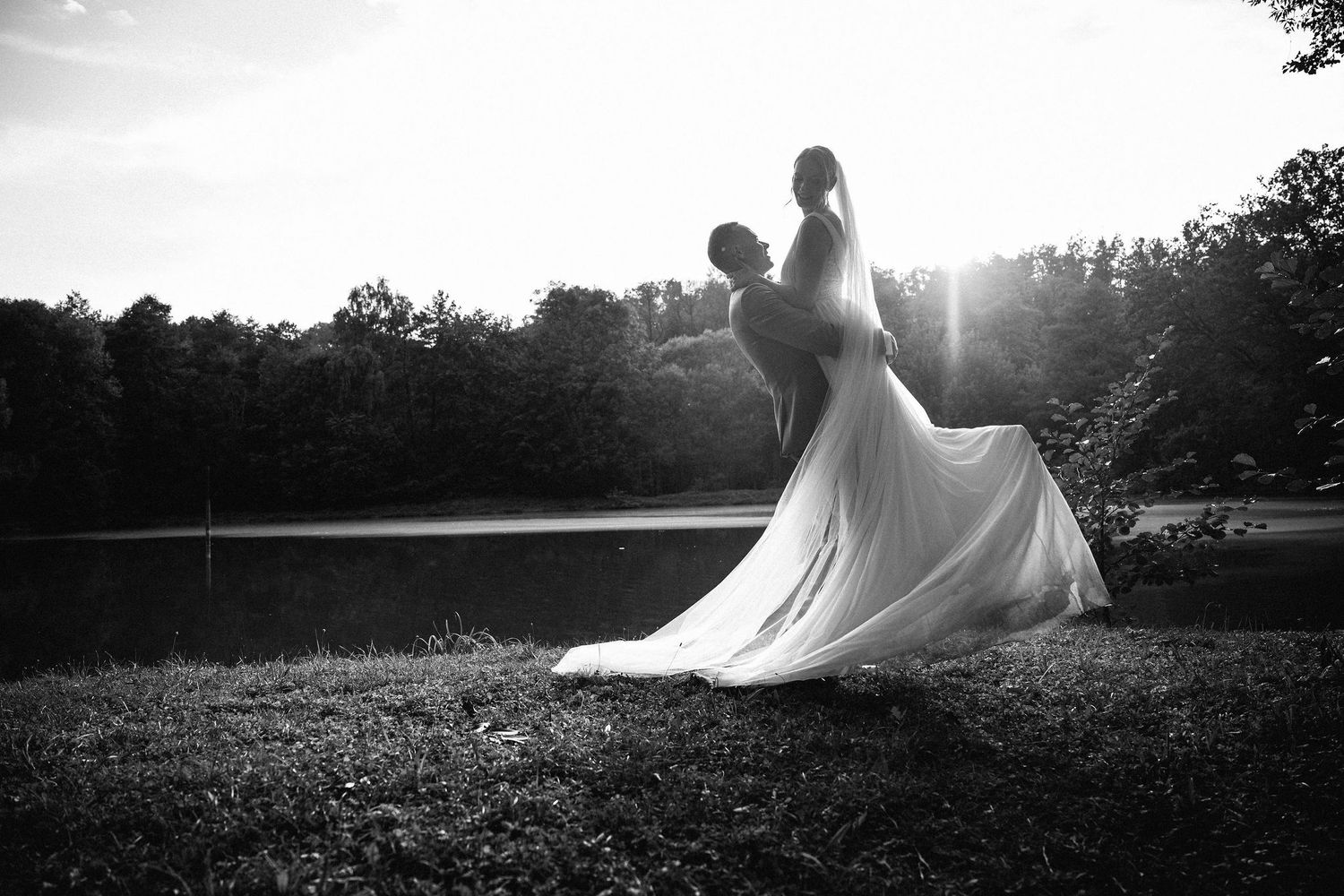 Artistic black and white silhouettes of a wedding party in a sunset field.