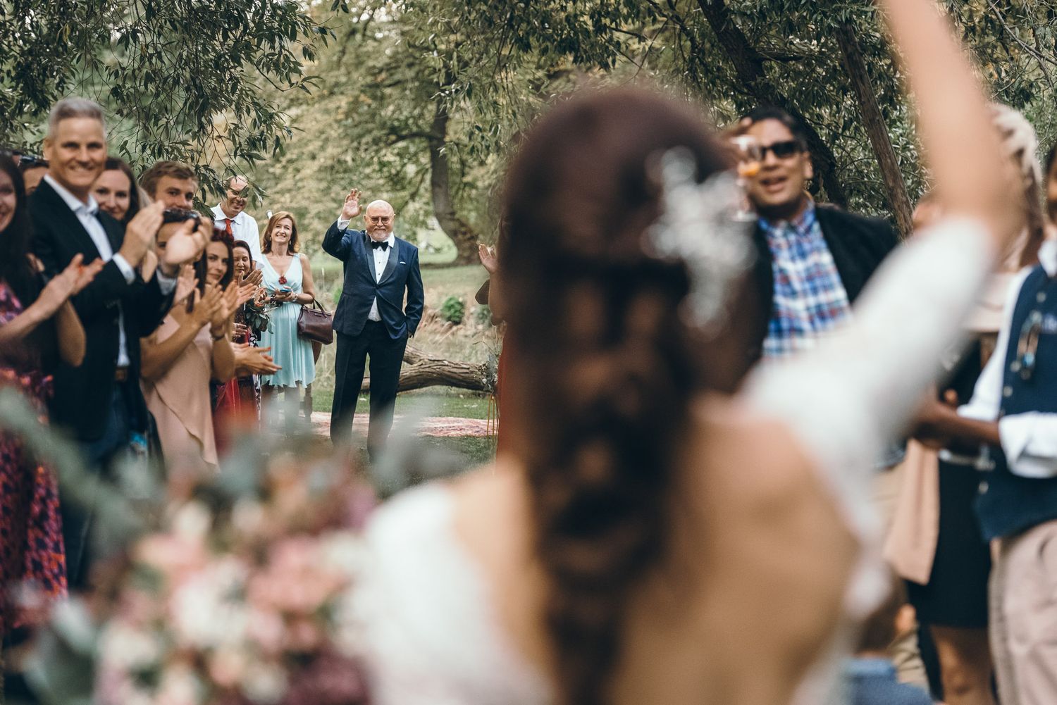 Wedding guests mingling outdoors during a sunny garden reception.