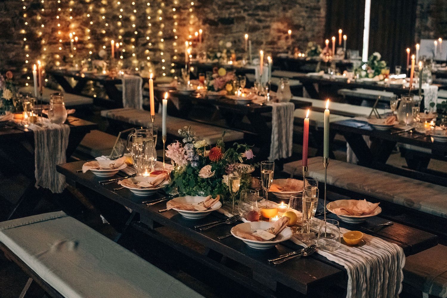Elegant wedding reception table setting with string lights and rustic decor.