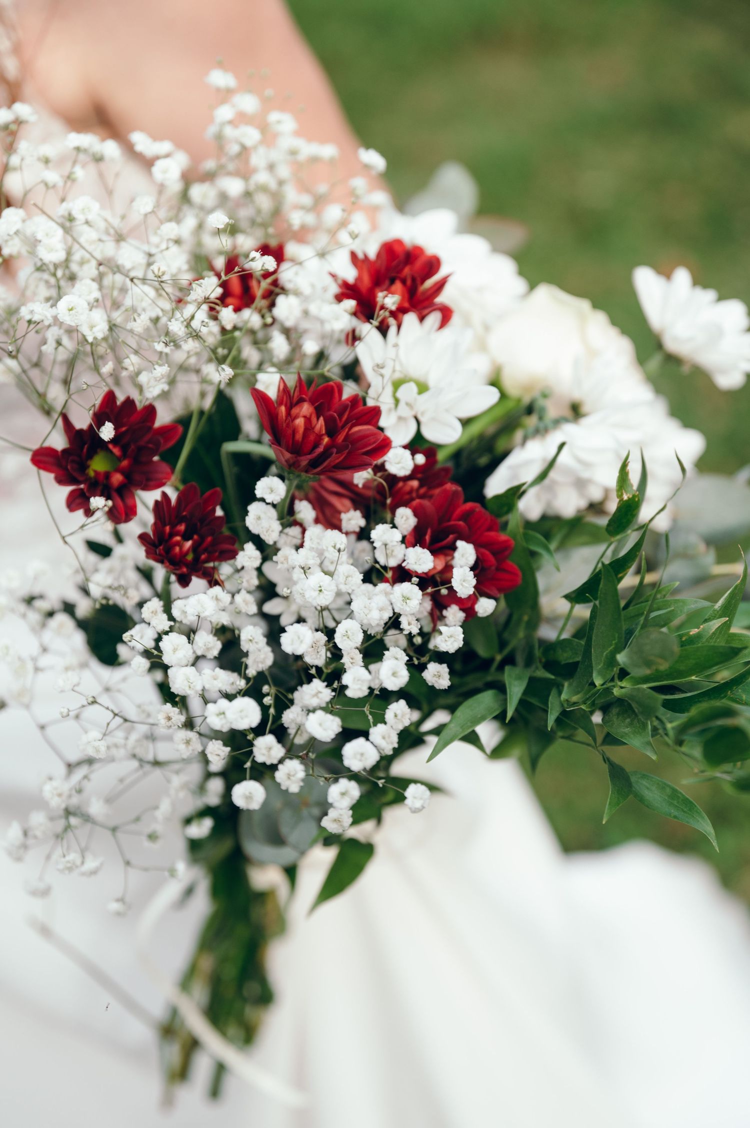 Close-up shots of a bridal bouquet featuring deep red dahlias and delicate white baby's breath flowers.