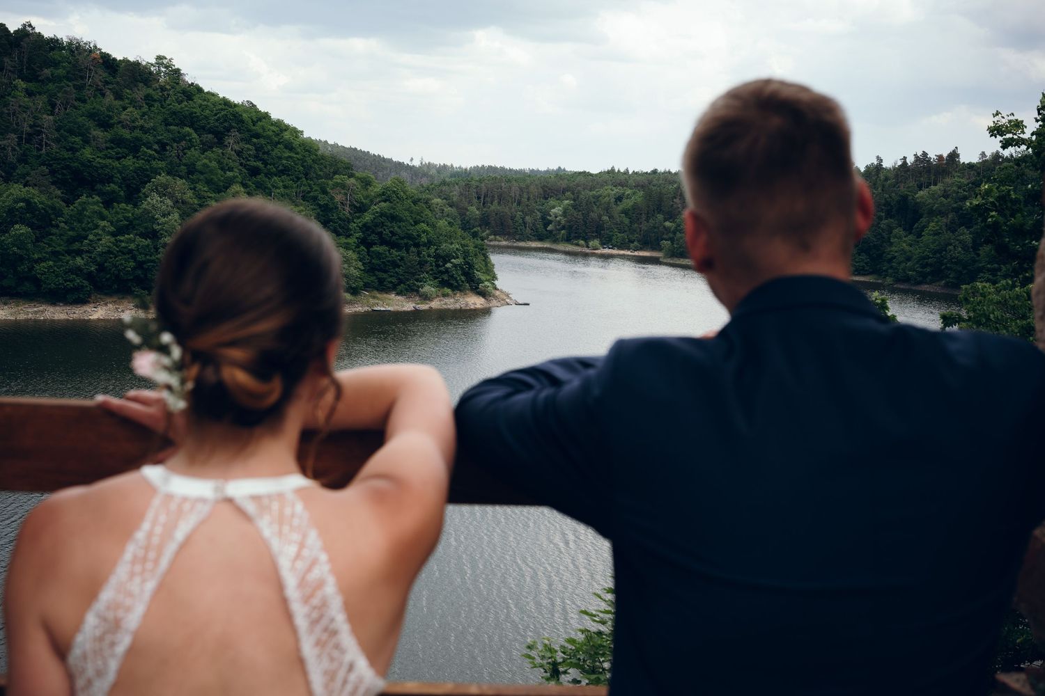 Wedding couple overlooking a scenic lake vista on their special day.