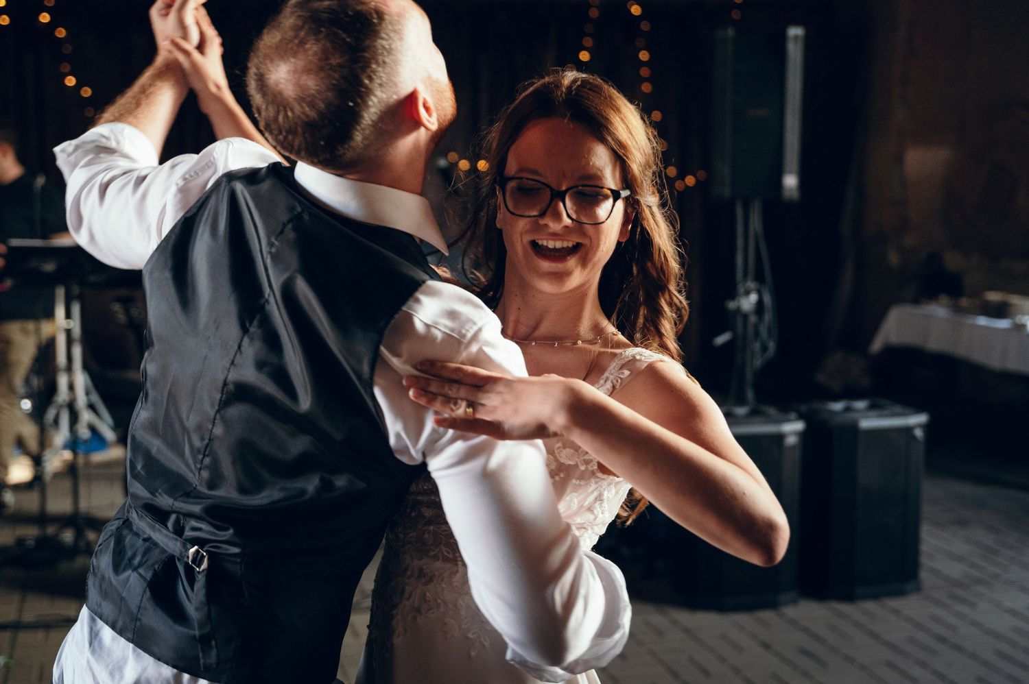 Couples dancing together at an evening wedding reception with twinkle lights.