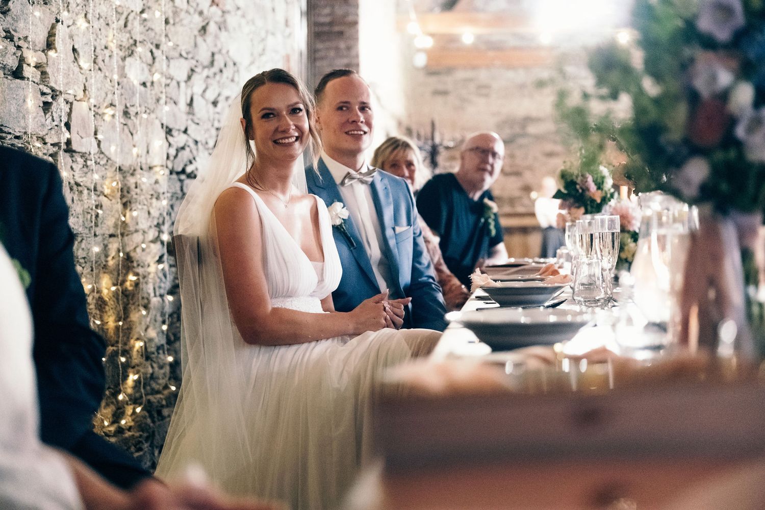 Elegant wedding reception dinner with stone wall backdrop and intimate lighting.