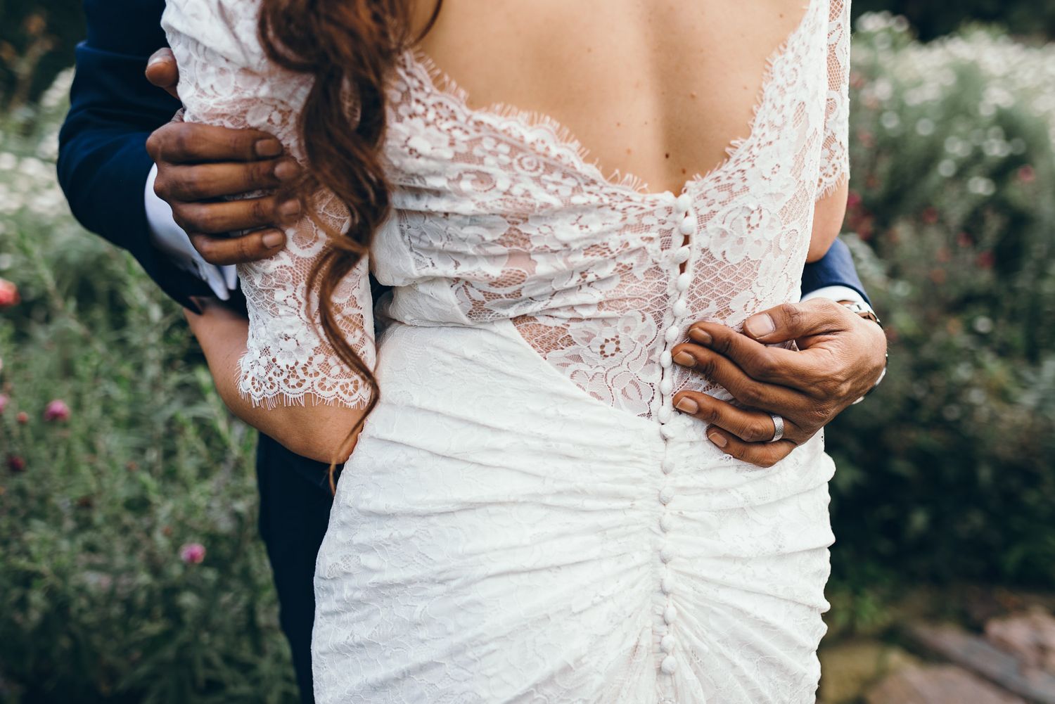 Close-up detail of a white lace wedding dress with intricate button details down the back.