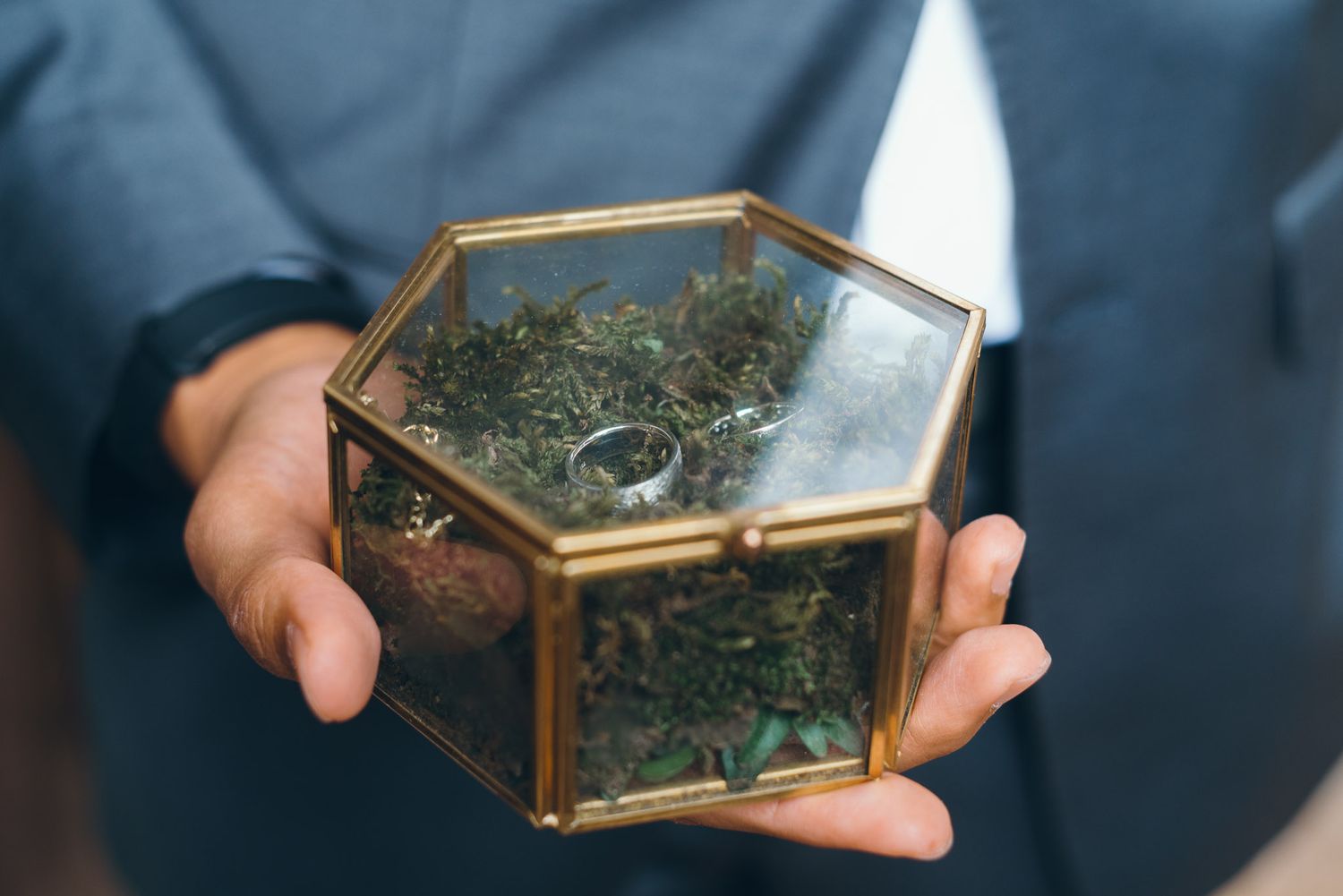 Close-up shots of decorative glass boxes being held at a wedding ceremony.