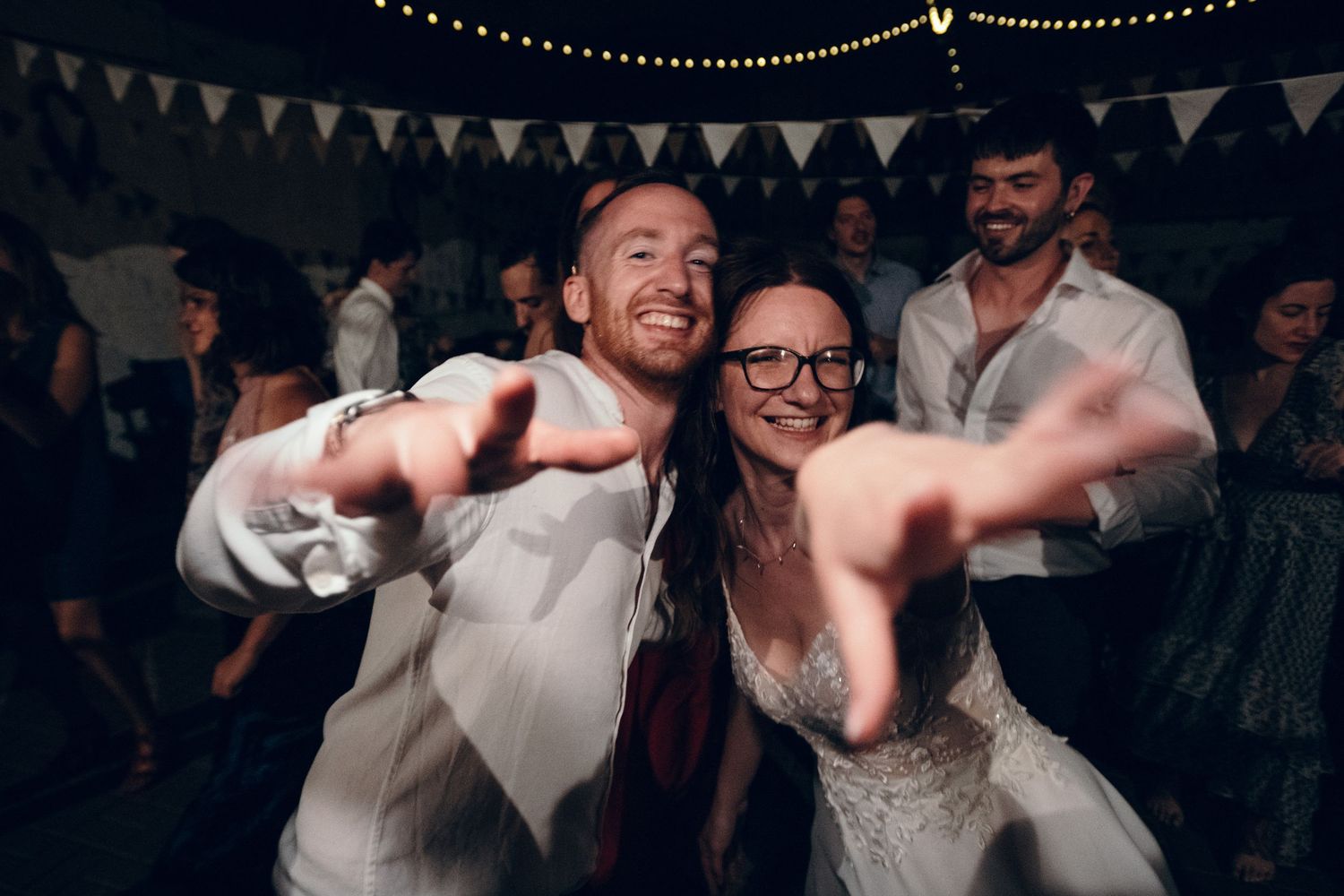 Wedding reception dance party with festive bunting decorations and string lights overhead.