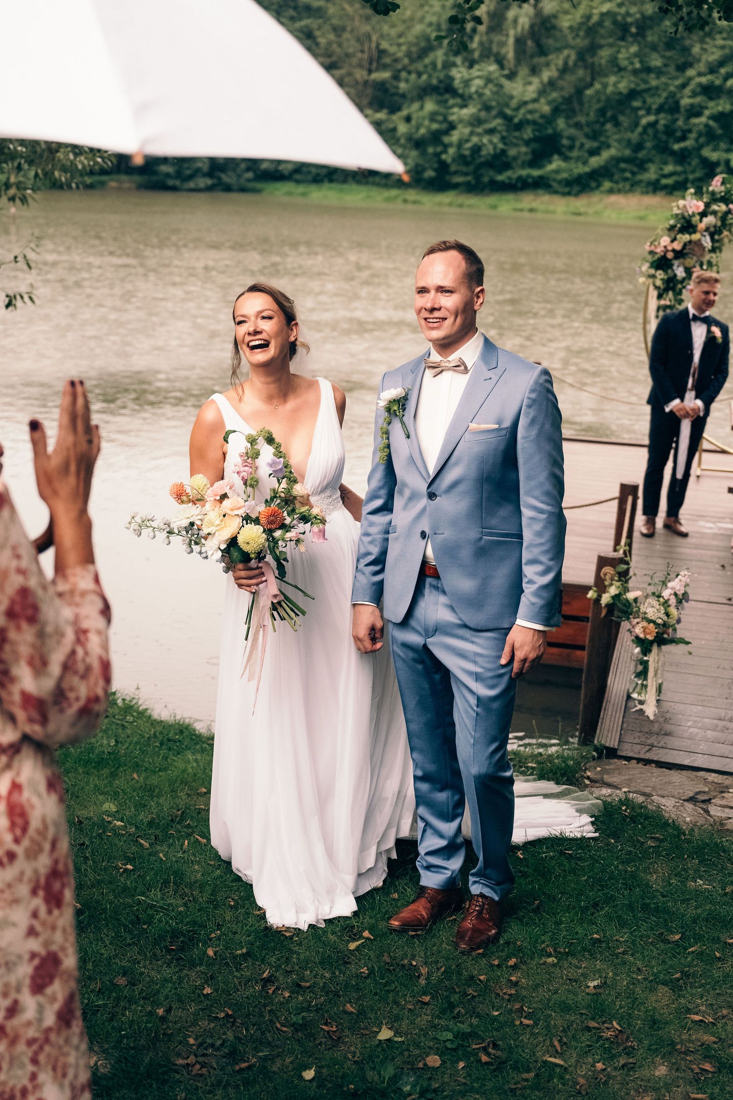 Newlyweds walking down aisle on wooden dock after lakeside ceremony.