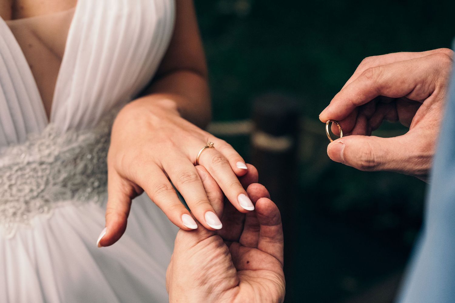Close-up of hands exchanging wedding rings during ceremony.