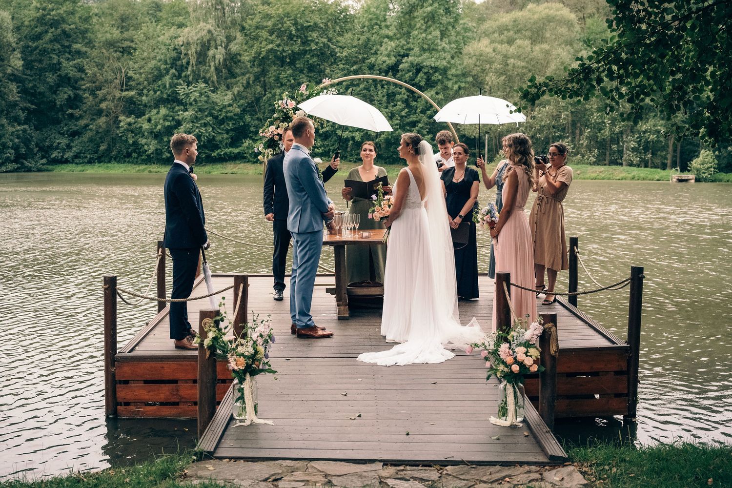 Lakeside wedding ceremony setup with wooden dock and white umbrellas.