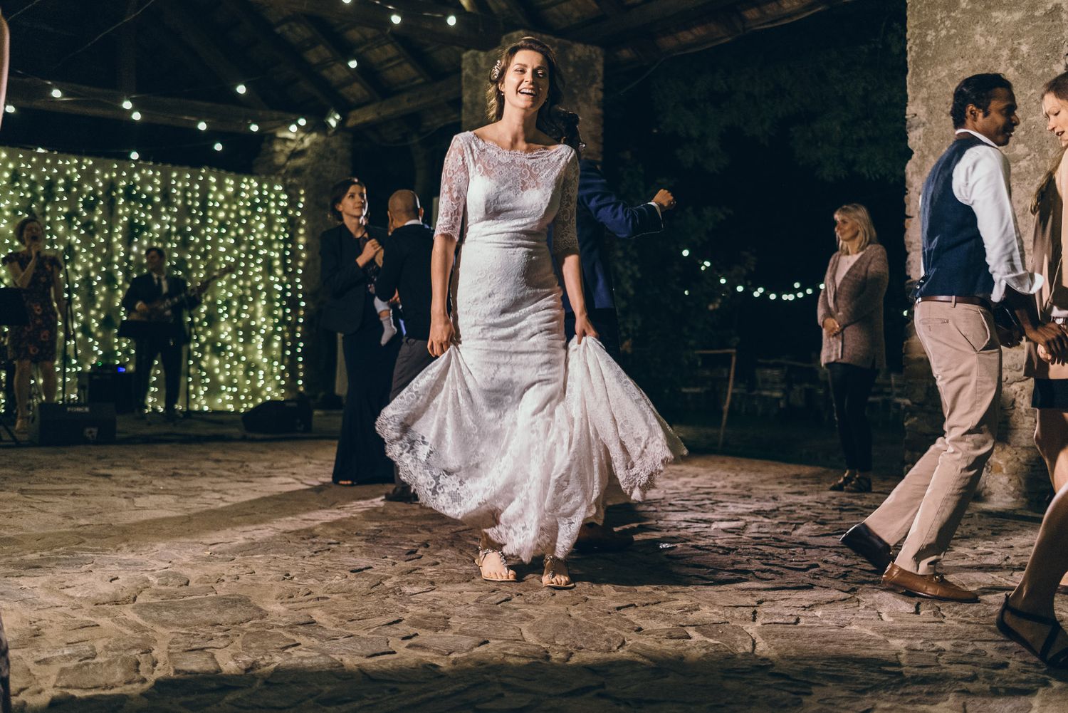A person in a white wedding dress twirls on the dance floor during reception celebrations.
