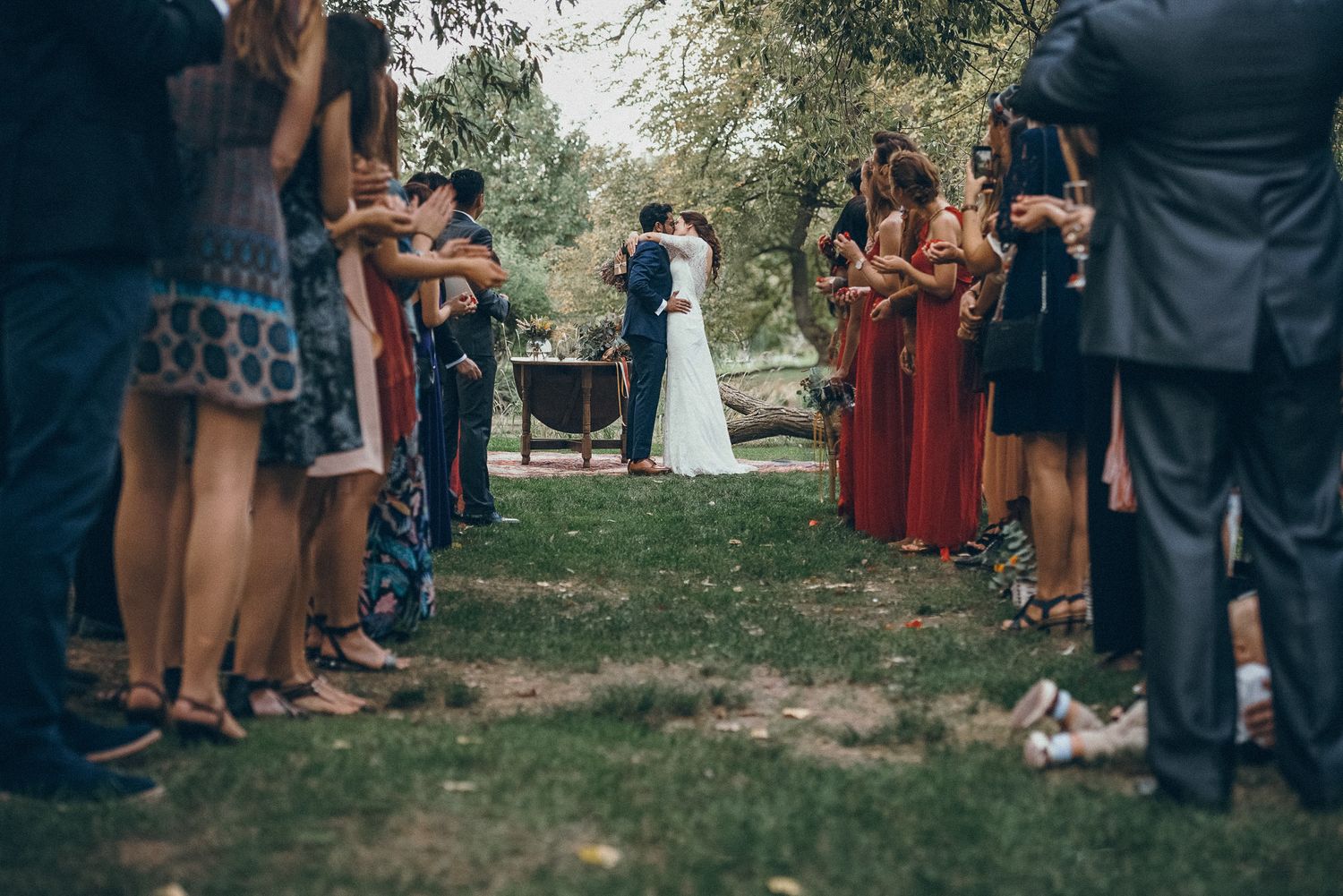Wedding guests gather on grass during an outdoor ceremony.