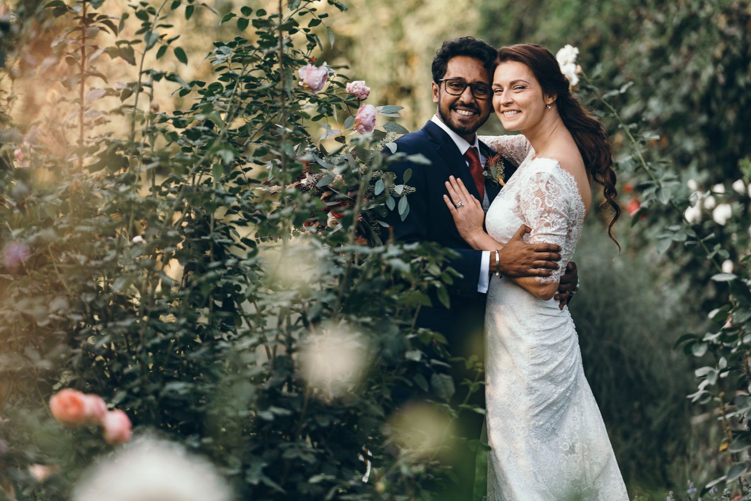 Newlyweds sharing intimate moments in a garden setting surrounded by greenery.