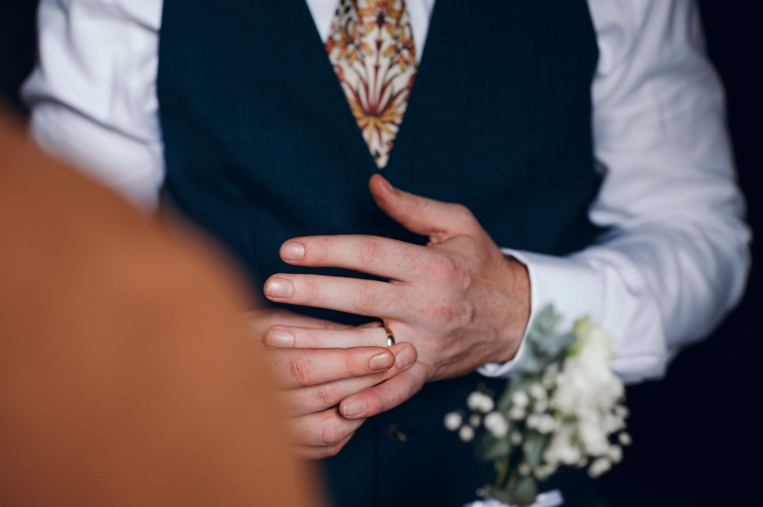 Close-up shots of formal attire and hands during wedding ceremony.